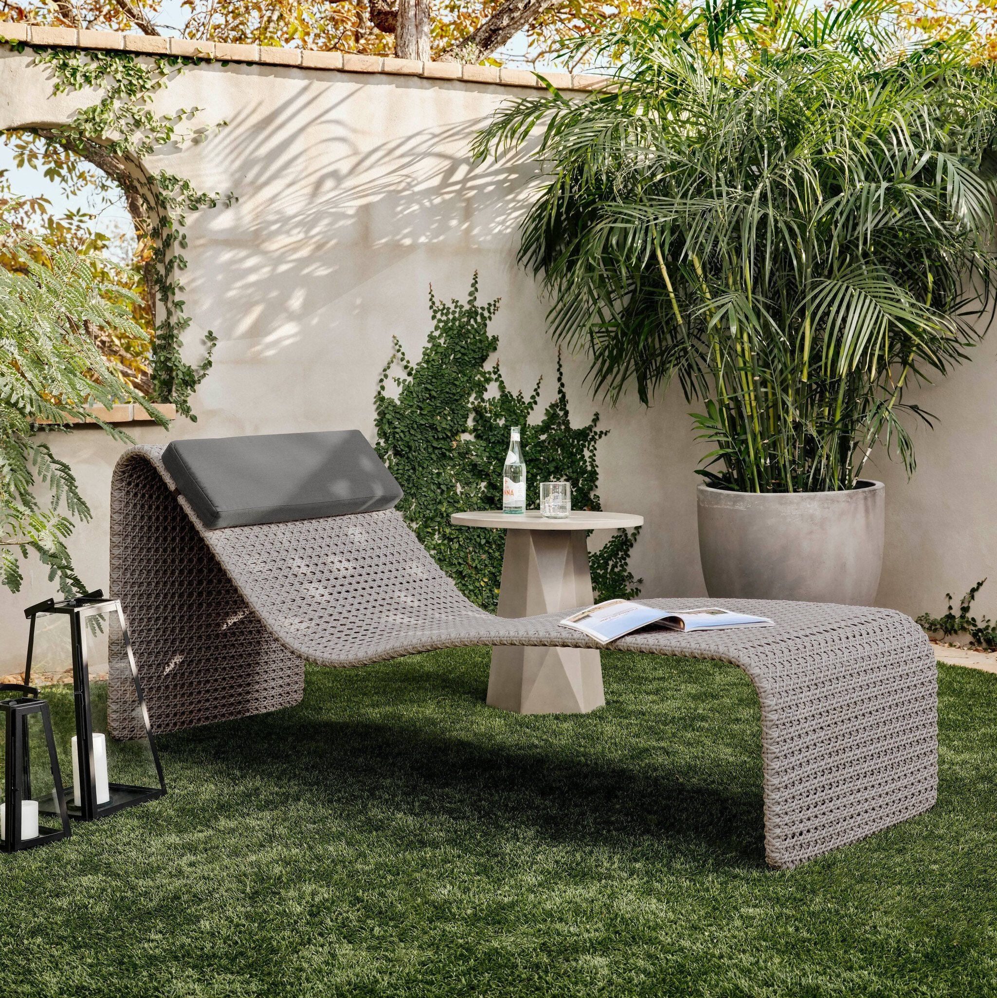 Modern outdoor lounge chair with a small table and plants in a garden setting
