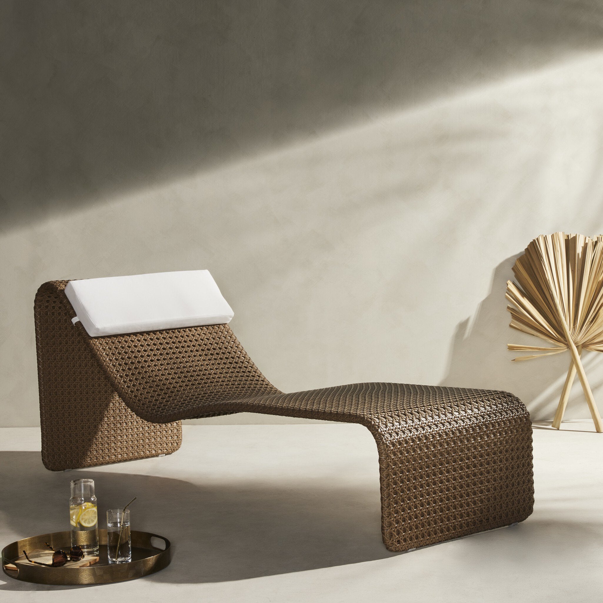 Modern wicker lounge chair with a white cushion in a minimalistic setting.