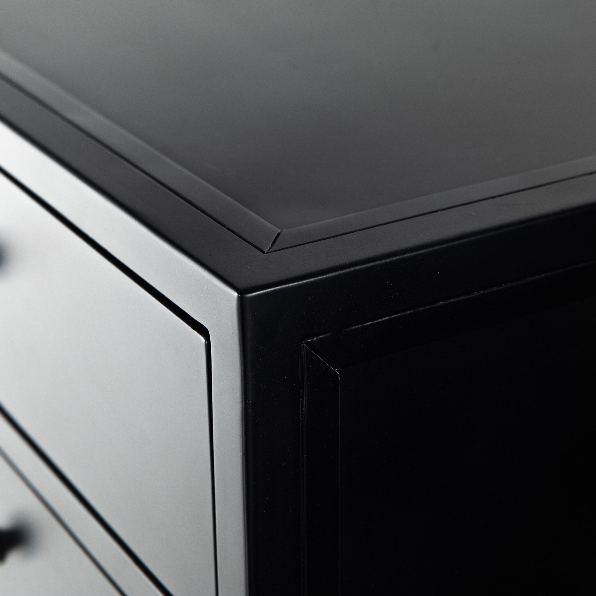 Close-up of a black cabinet corner with a reflective surface.