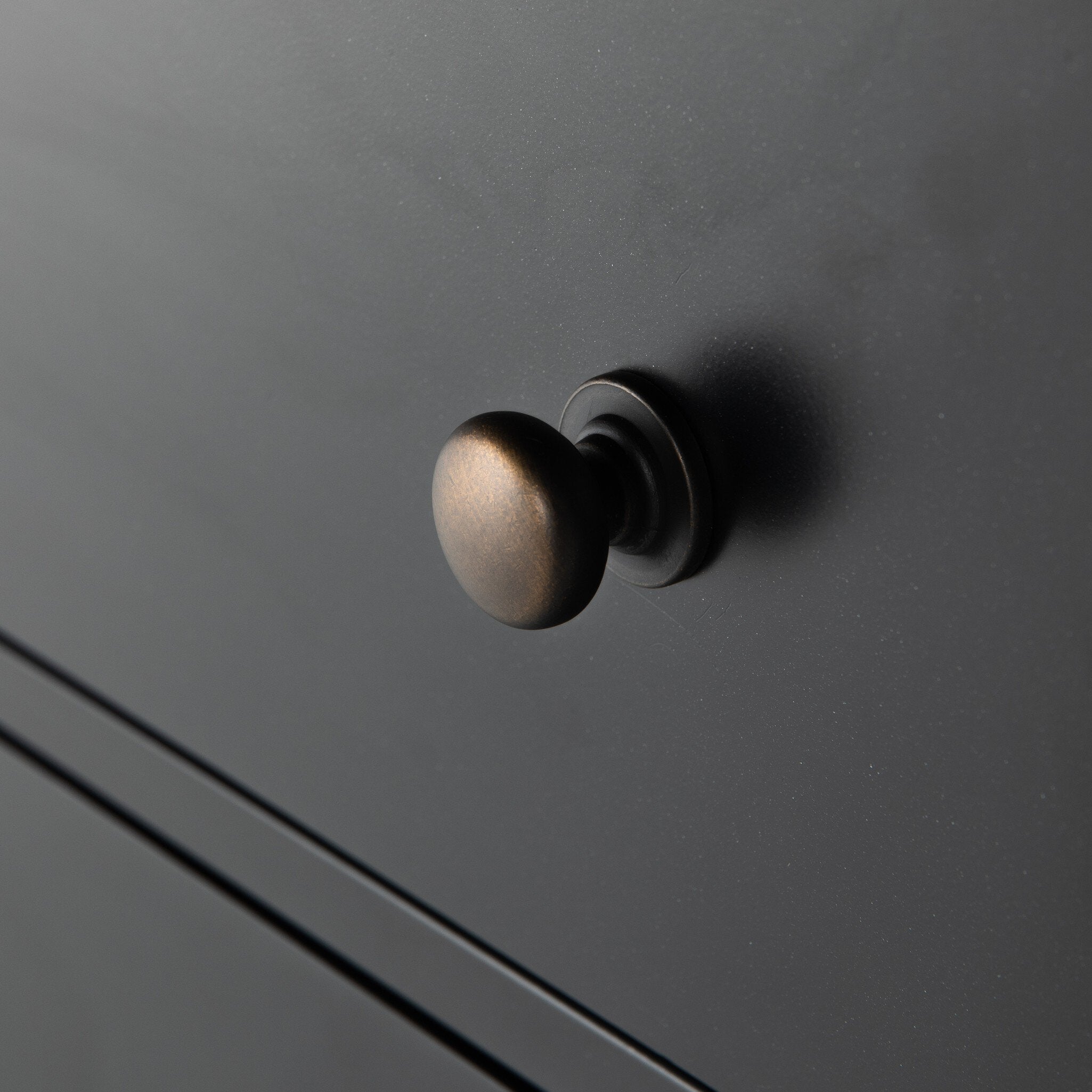 Bronze drawer knob on a black dresser