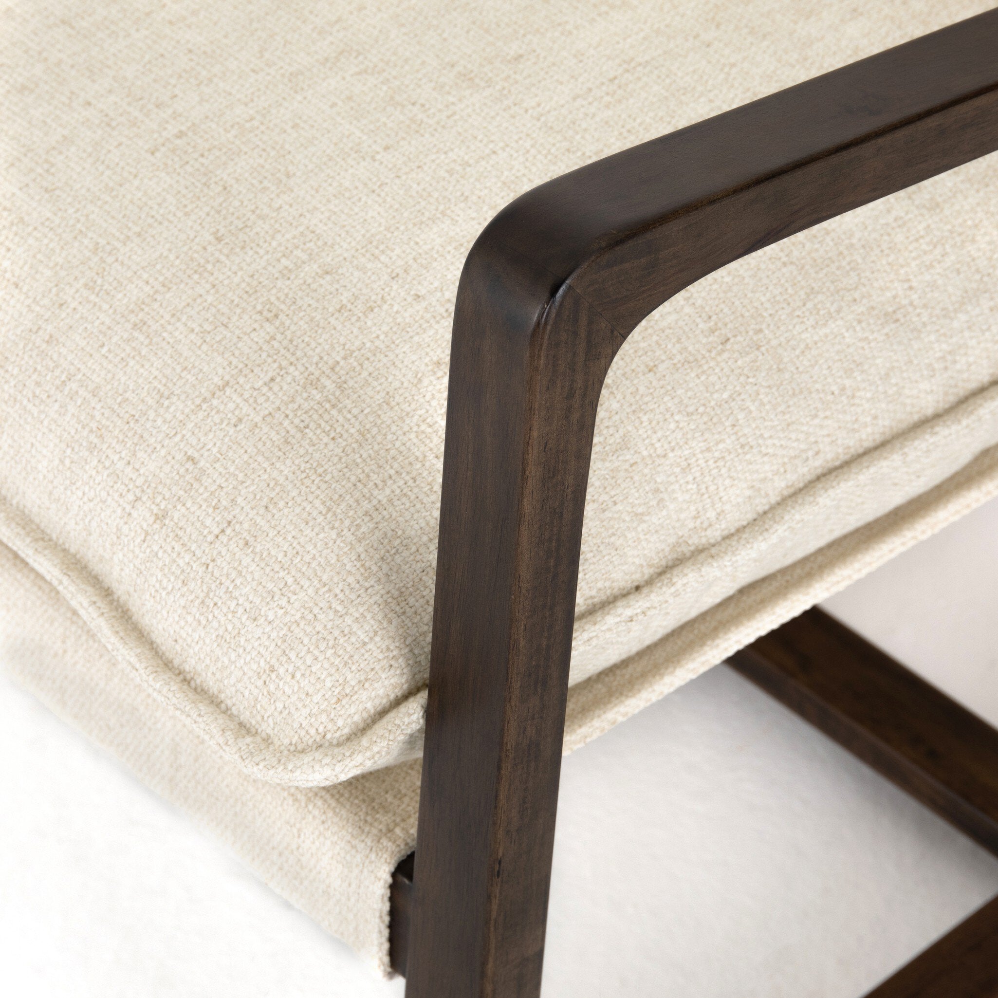 Close-up of a chair with wooden frame and beige cushion on a white background