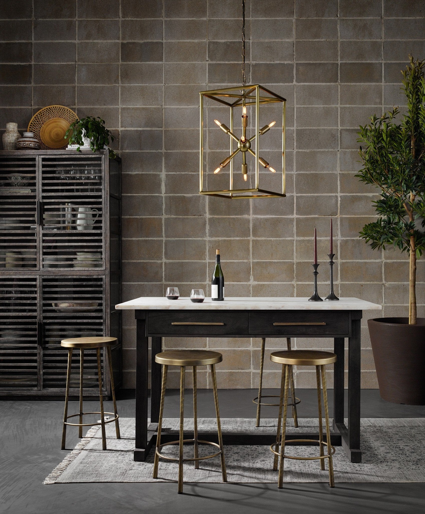 Modern table with marble countertop, gold pendant light, and brass bar stools.