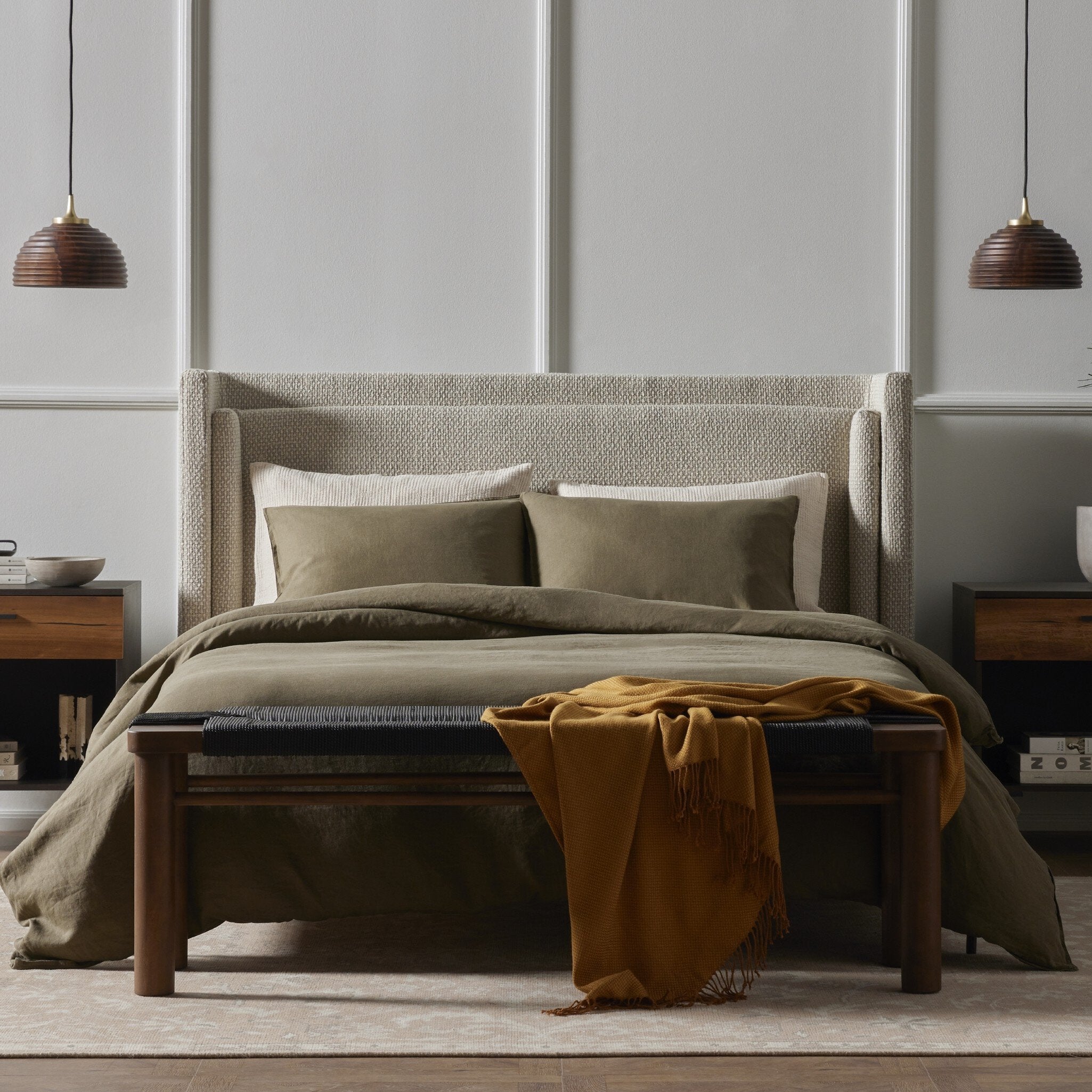 Bedroom with a bed featuring green bedding and a wooden headboard, with two pendant lights hanging above.