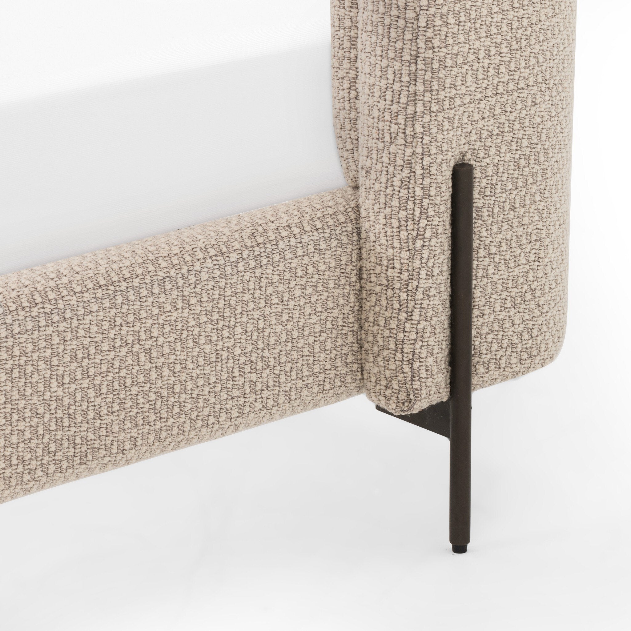 Close-up of a textured beige bed frame with a black metal leg on a white background