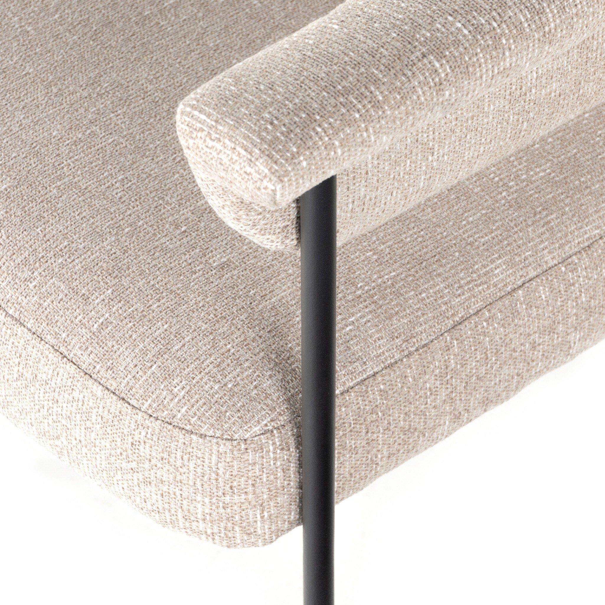 Close-up of a textured beige sofa corner with a black metal leg.