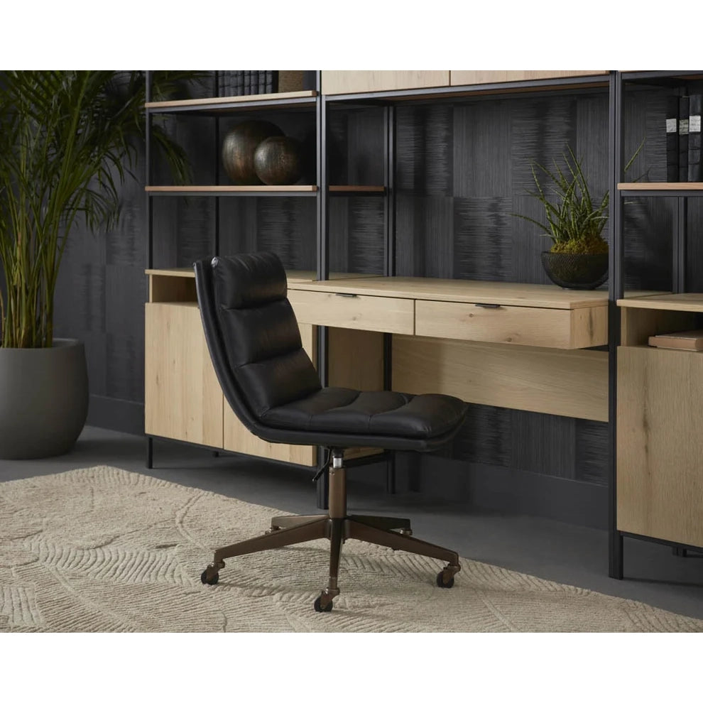 Black office chair in front of a wooden desk with shelves in a room setting.