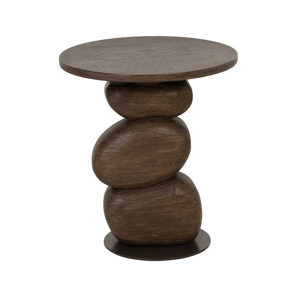 A dark brown wooden side table with a round top and a sculptural, stacked stone-like pedestal base on a plain white background.