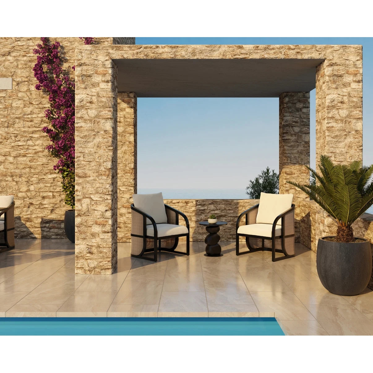 Modern outdoor patio furniture set featuring two black-framed armchairs with off-white cushions, a small round dark side table, and a stone archway structure overlooking a pool and sea.