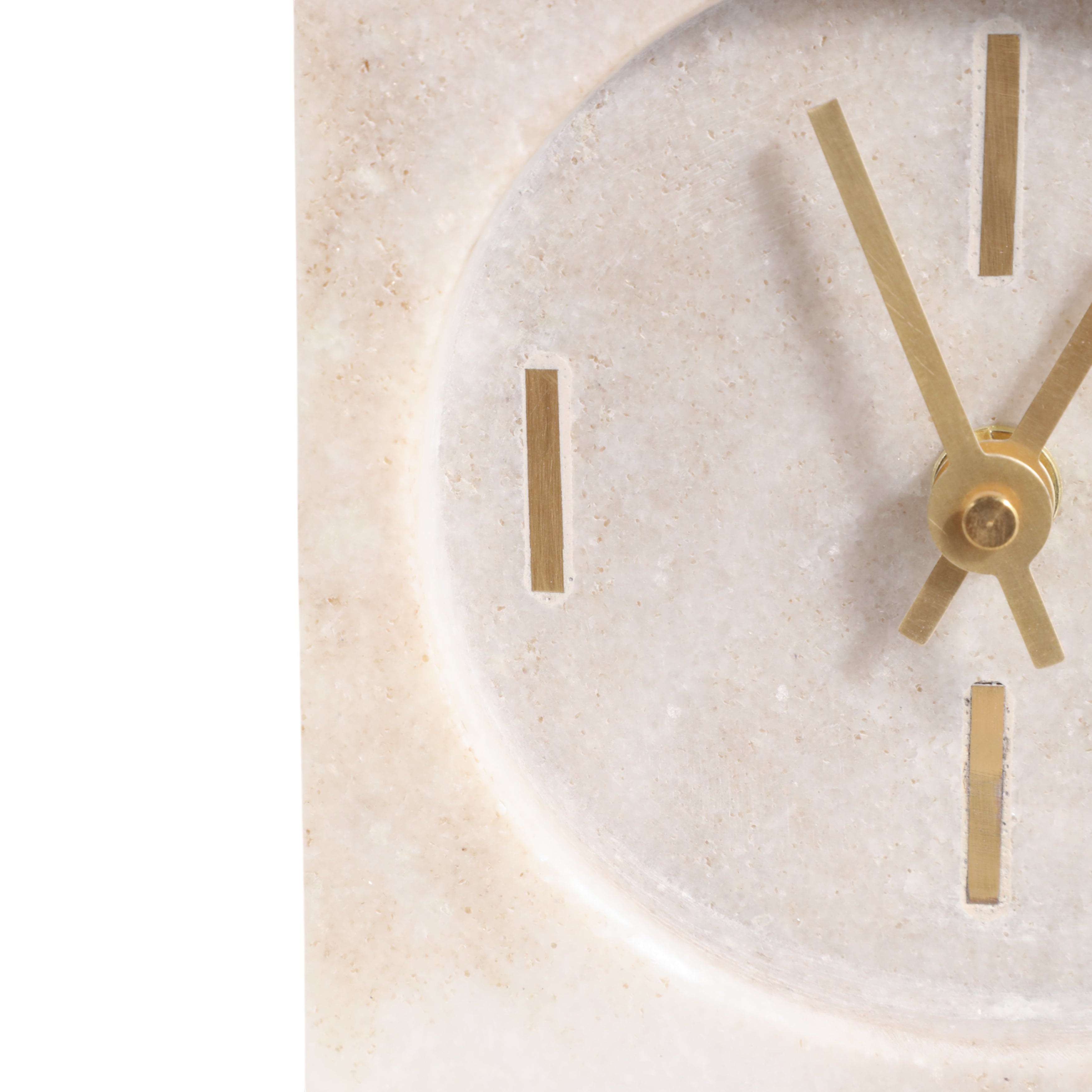 Close-up of a clock with gold hands on a light stone background