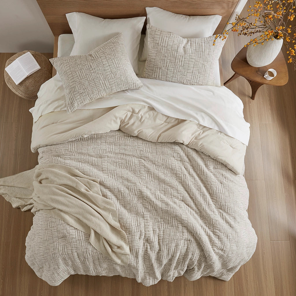 Neatly made bed with beige and white bedding in a bedroom setting.