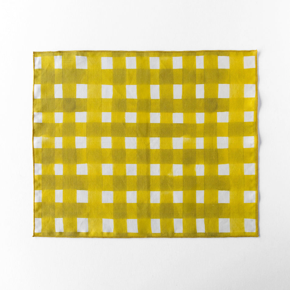 Yellow and white checkered linen placemat on a white background