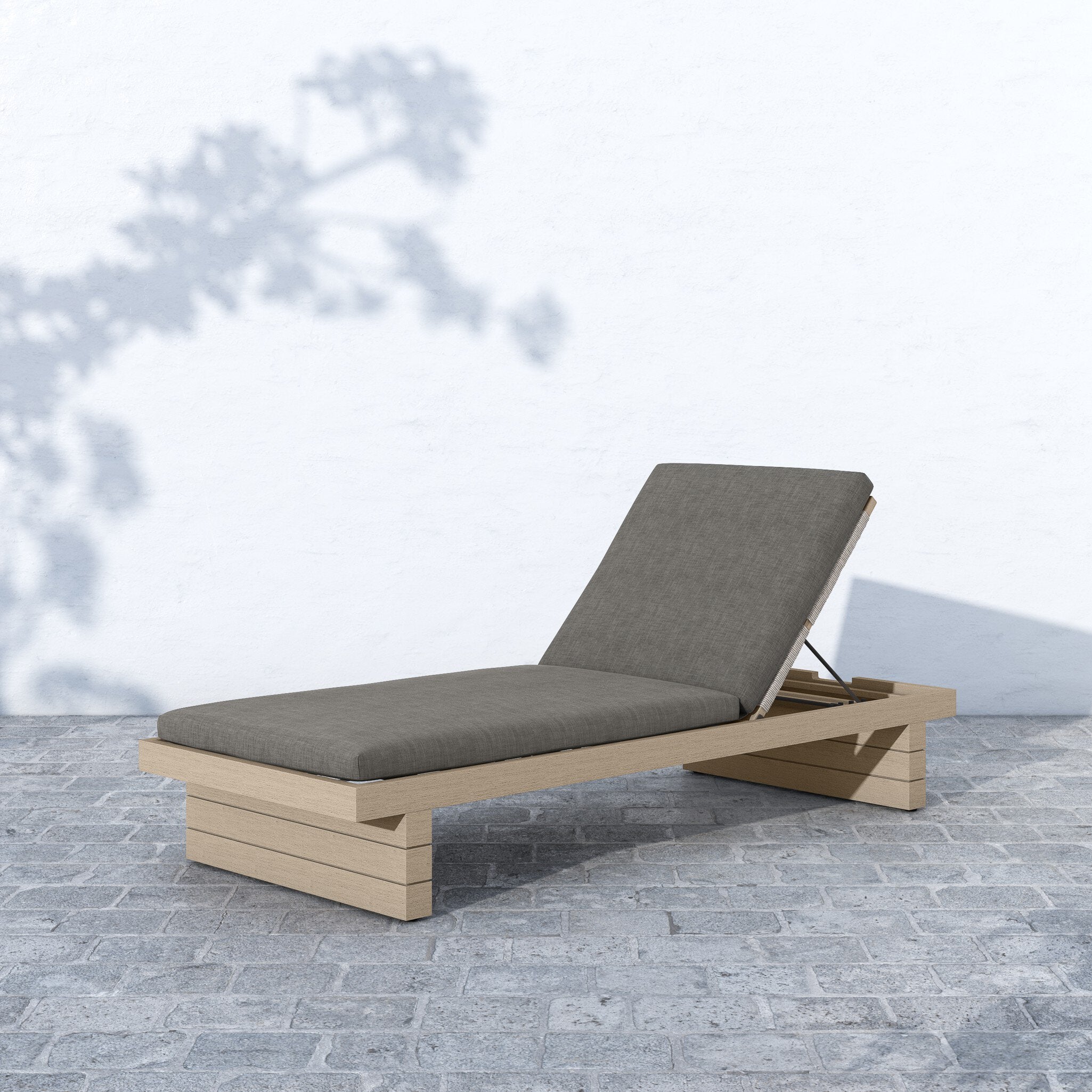 Beige outdoor lounge chair with gray cushion on a stone patio