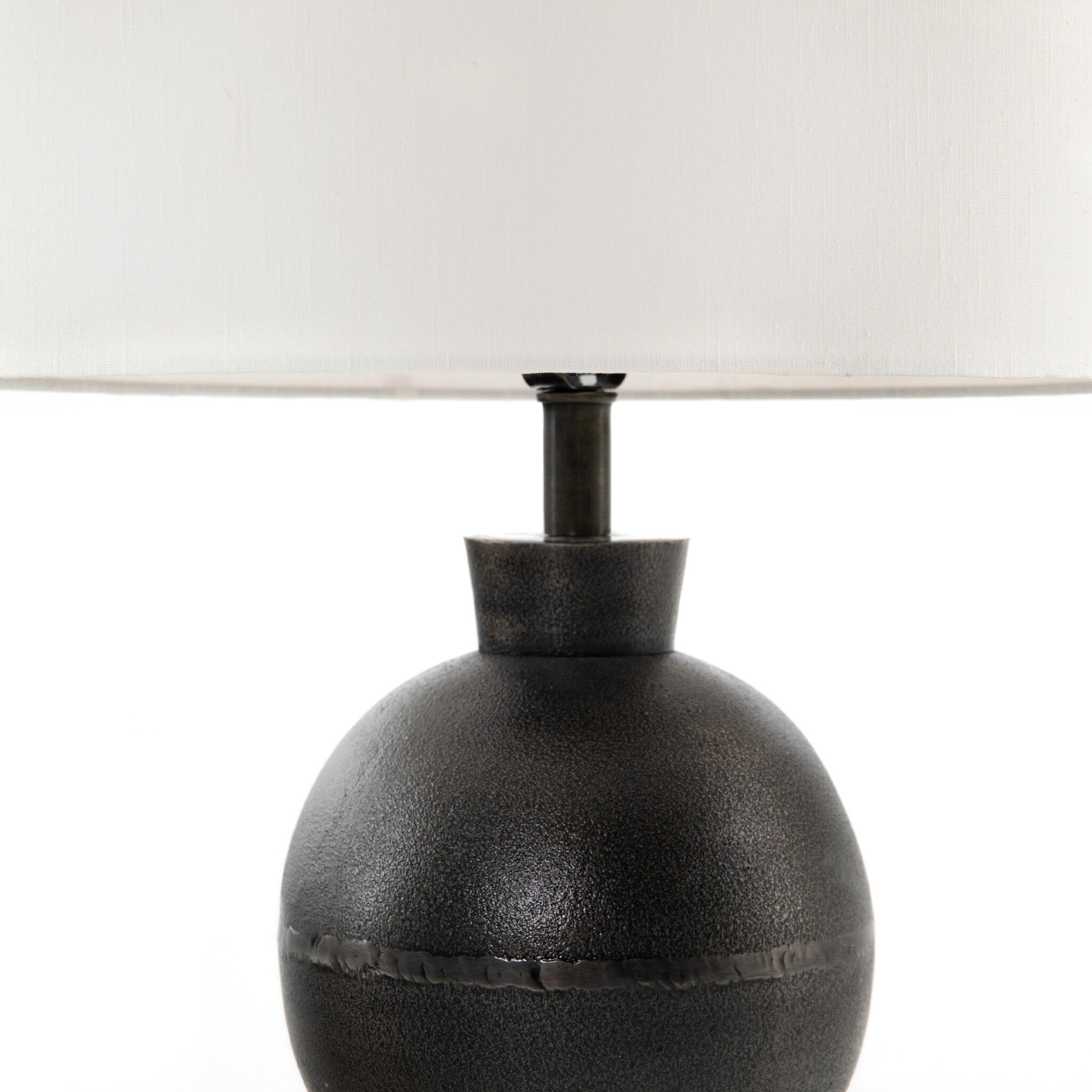 Black textured table lamp with a white lampshade on a white background