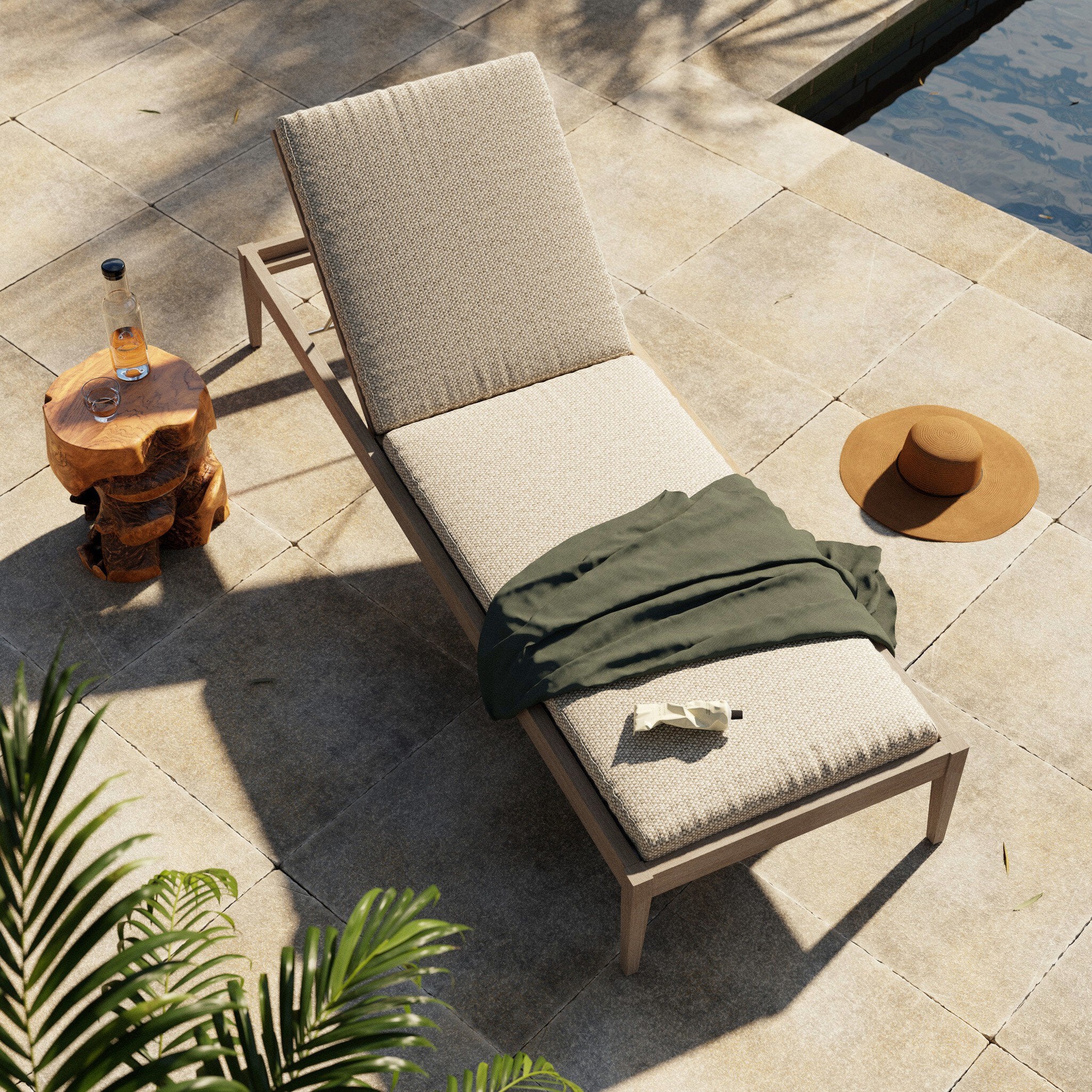 Beige outdoor lounge chair with a green towel on a stone patio by a pool.