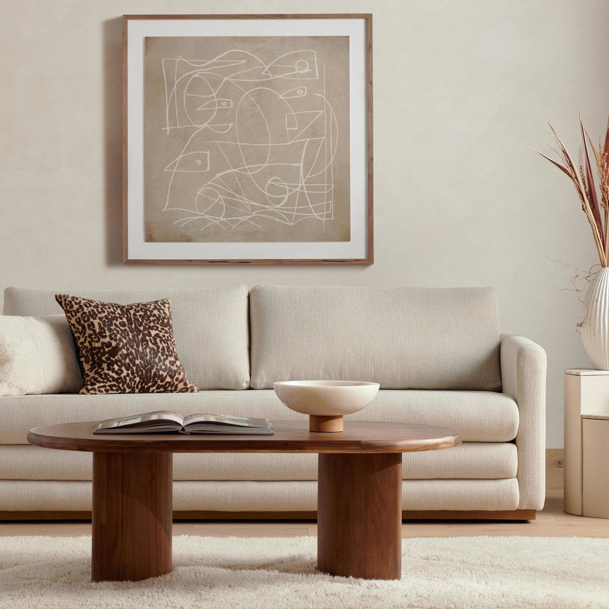 Living room with a beige sofa, wooden coffee table, and abstract art on the wall.