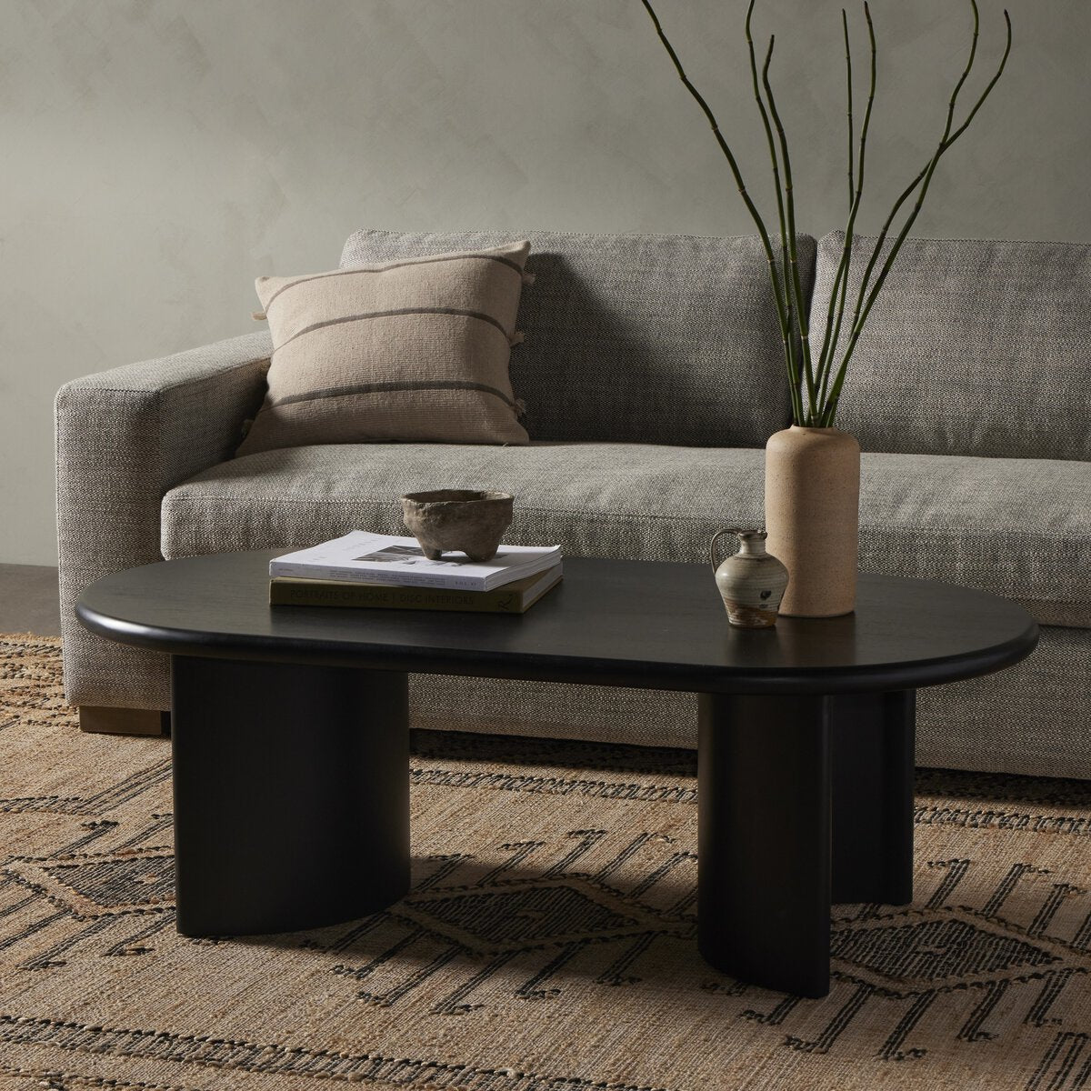 Living room with a gray sofa, black coffee table, and decorative items.