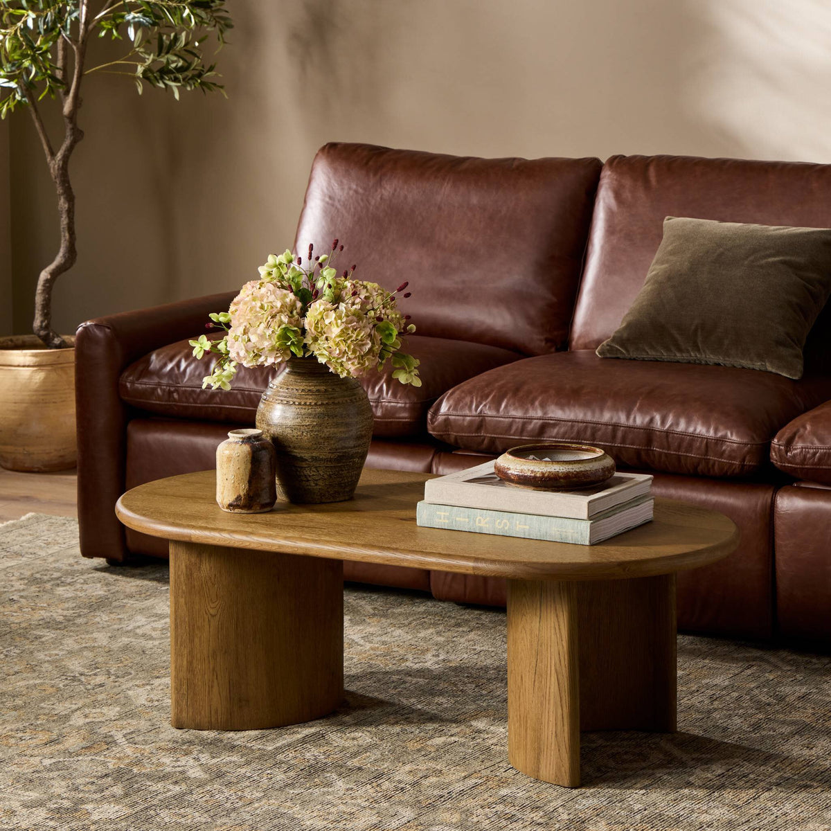 Brown leather sofa with a wooden coffee table and decorative items in a living room setting.