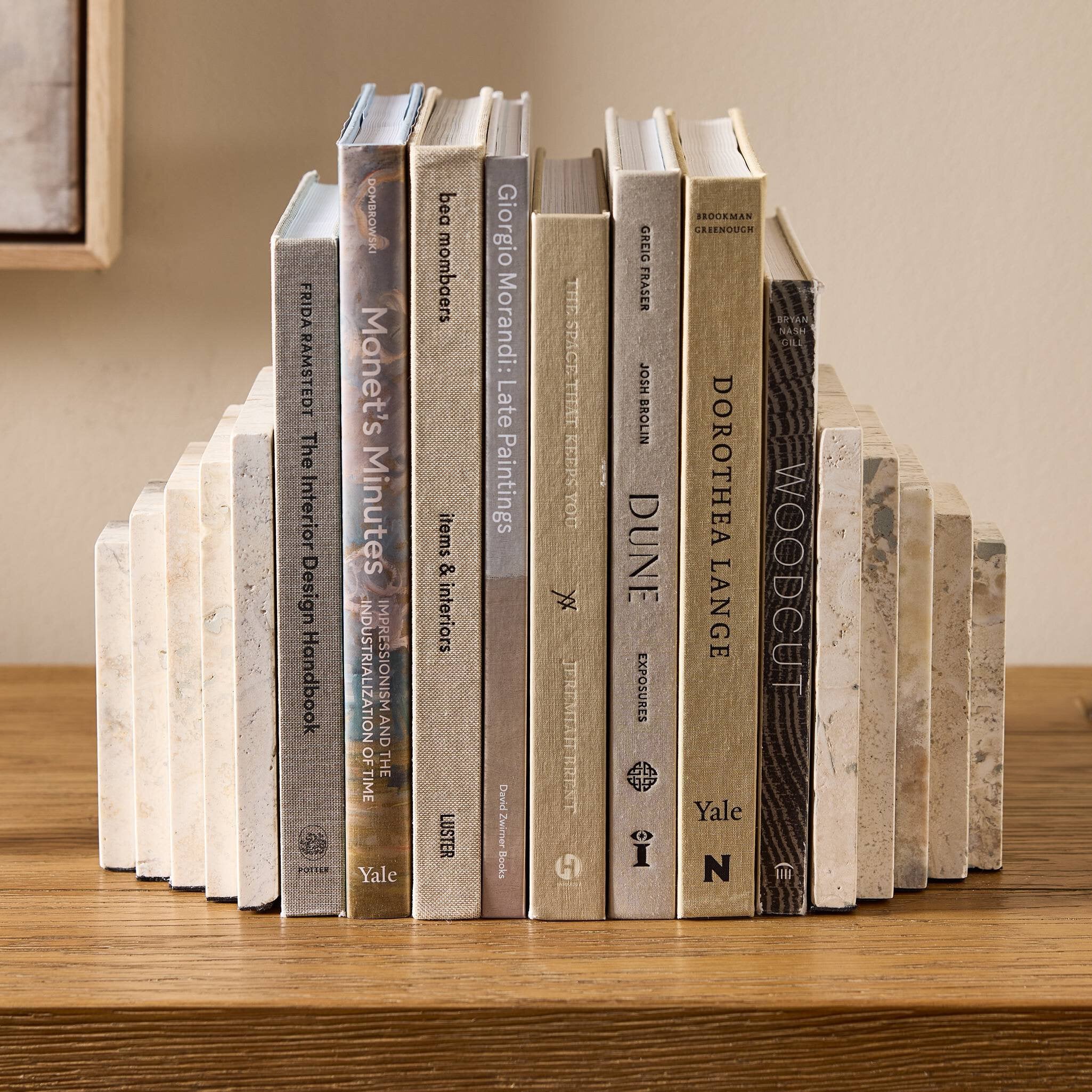 Row of books with stone bookends arranged on a wooden surface.