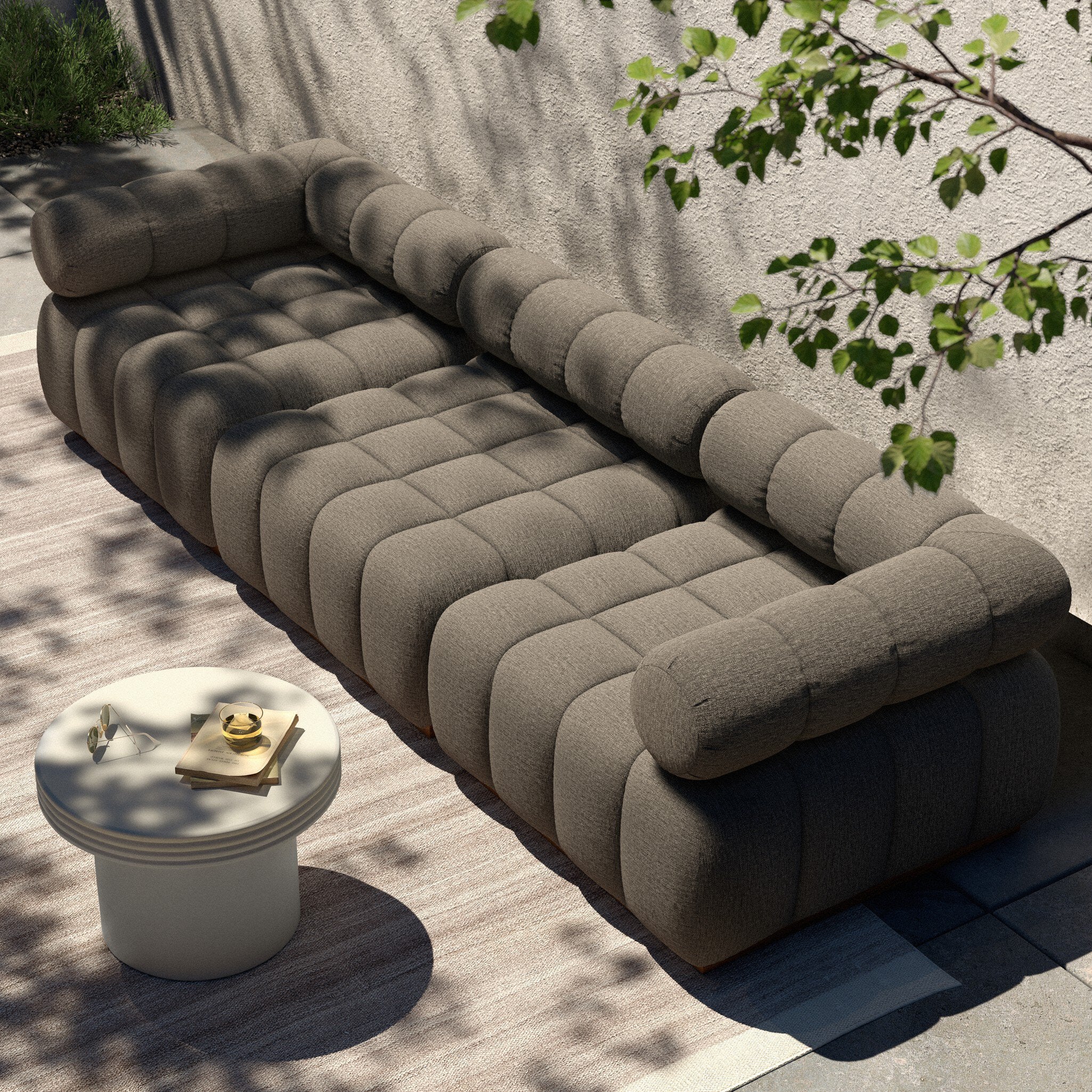 Brown sectional sofa outdoors with a small table and greenery.