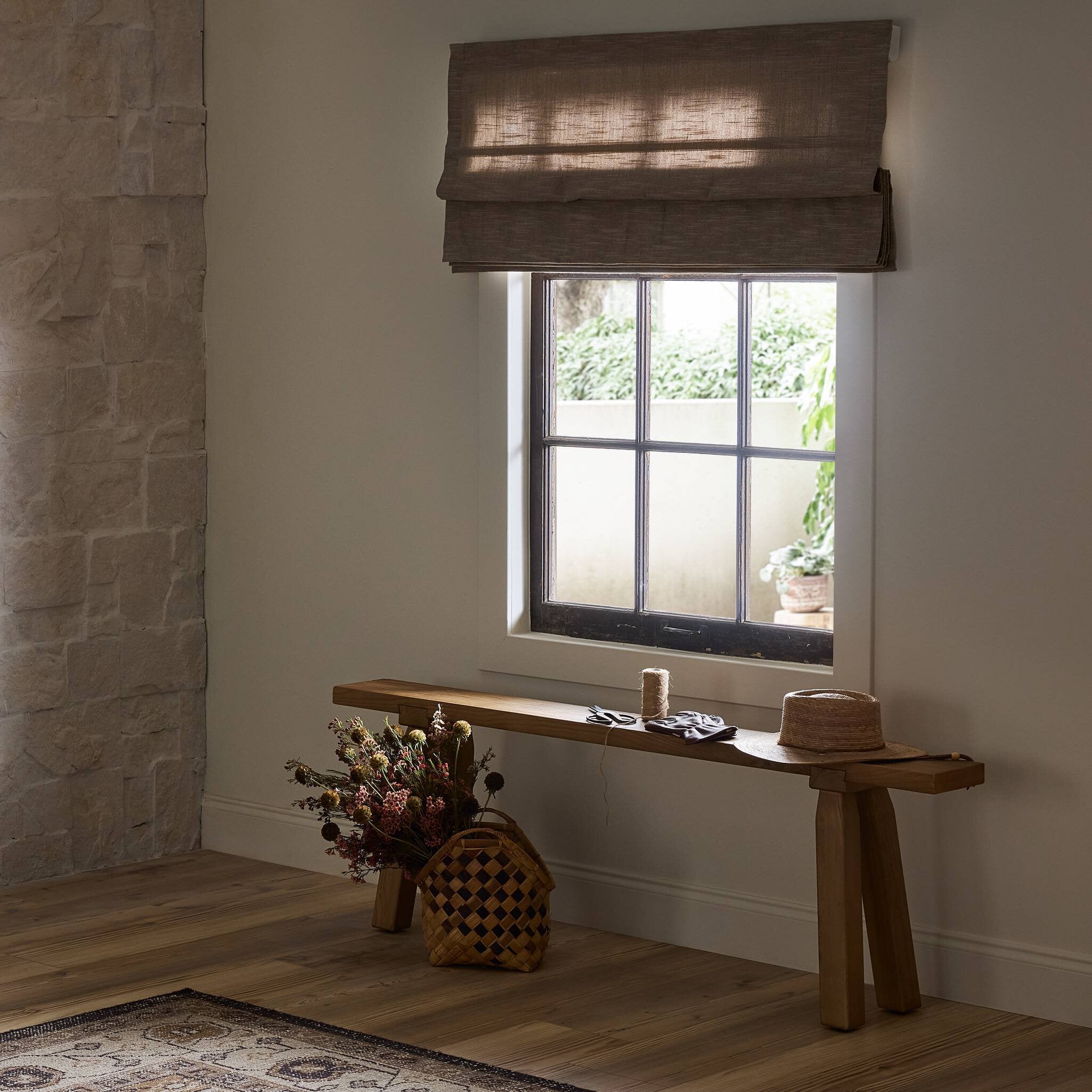 Wooden bench with decorative items against a stone wall and window.