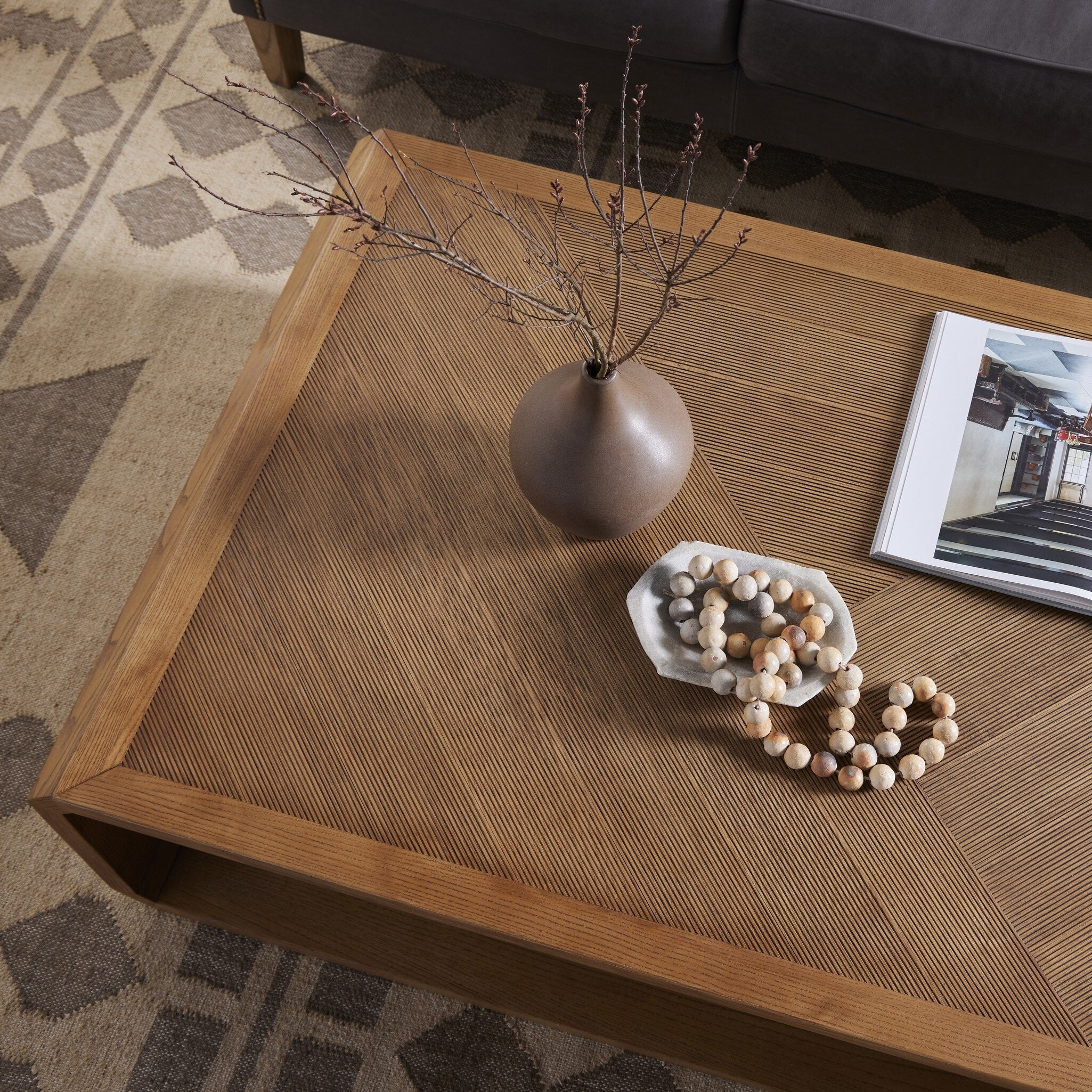 Wooden coffee table with decorative items including a vase, beads, and a framed picture on a patterned rug.