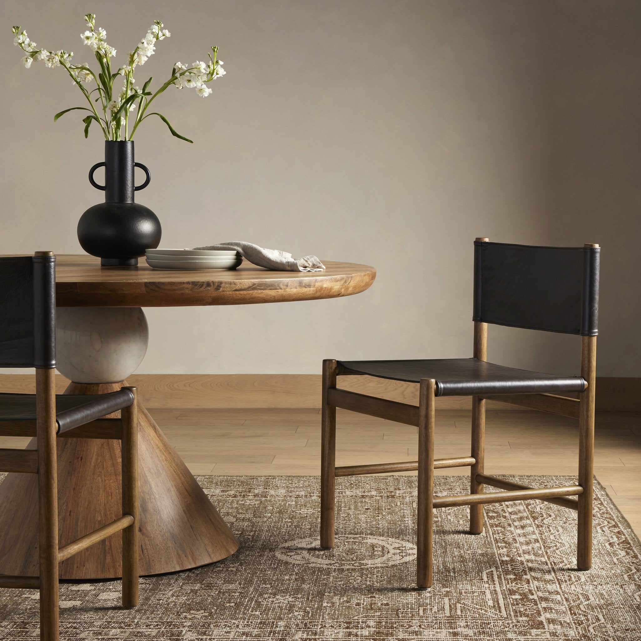 Dining room with wooden table and chairs, vase with flowers on the table.