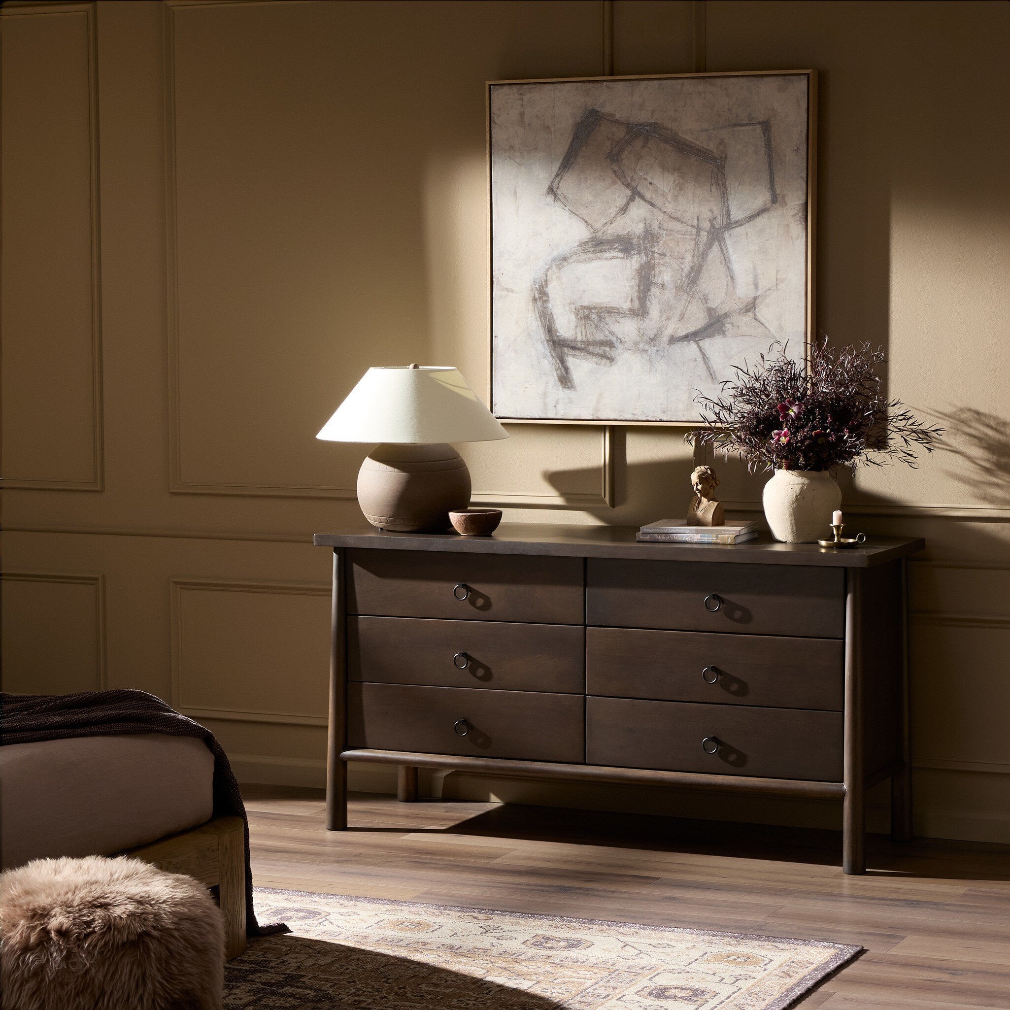 Dresser with lamp and decor in a room with abstract art on the wall