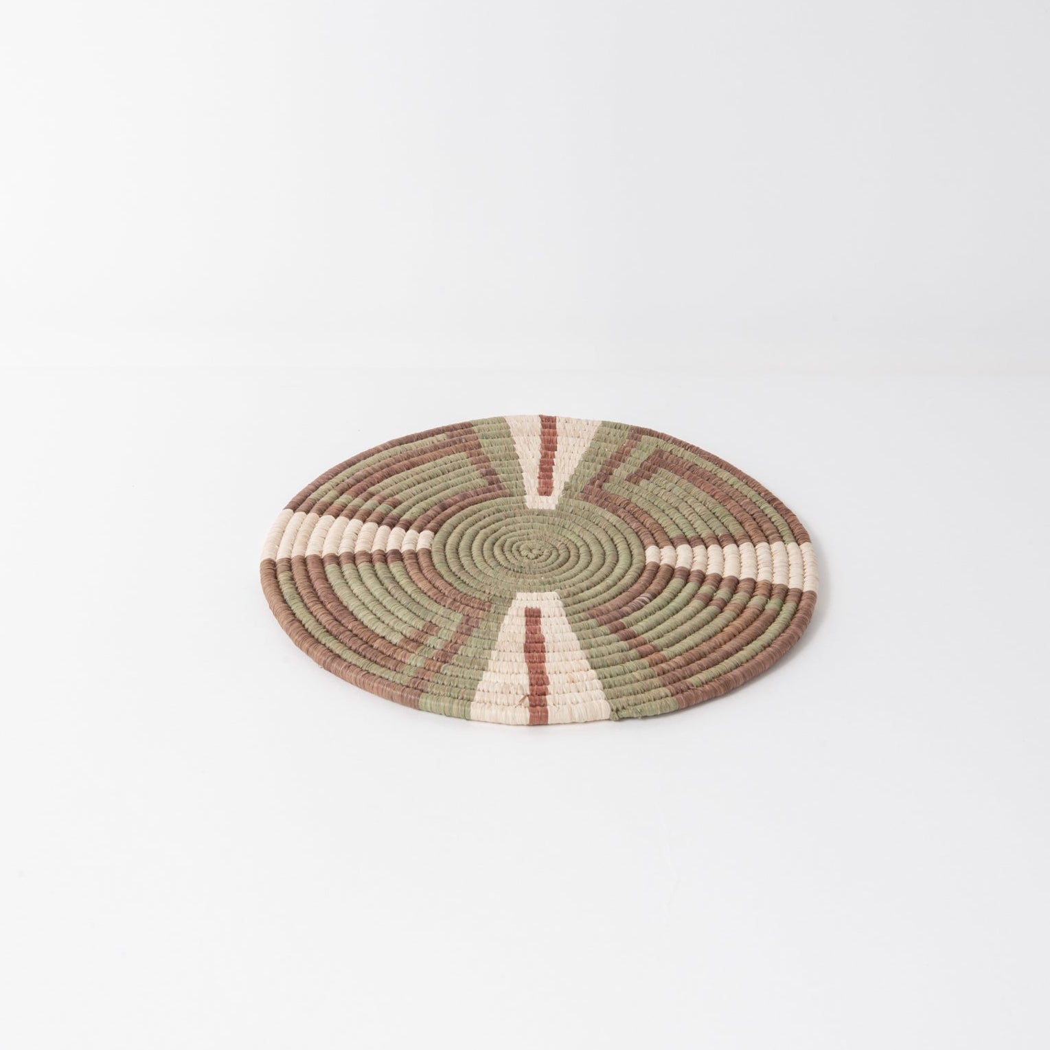 Round woven trivet with concentric circle pattern on a white background
