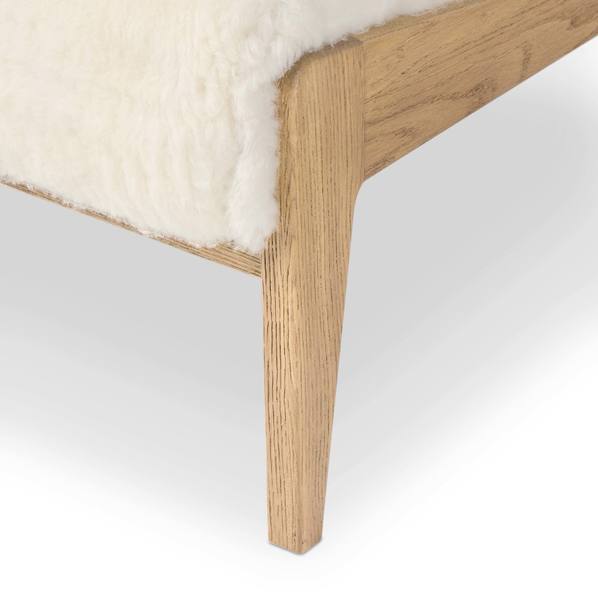 Close-up of a wooden chair with a white cushion on a light gray background