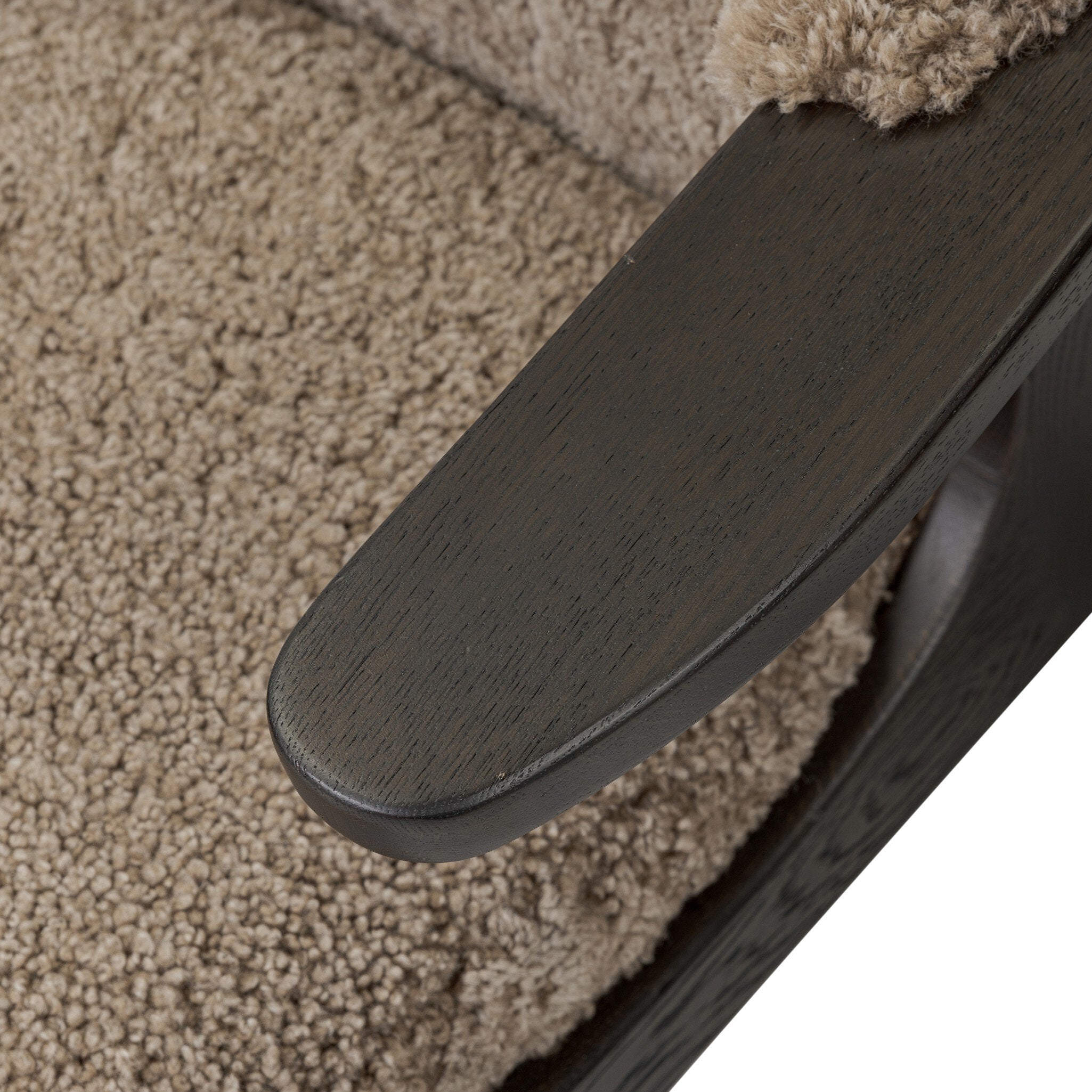 Close-up of a dark wooden armrest on a textured surface