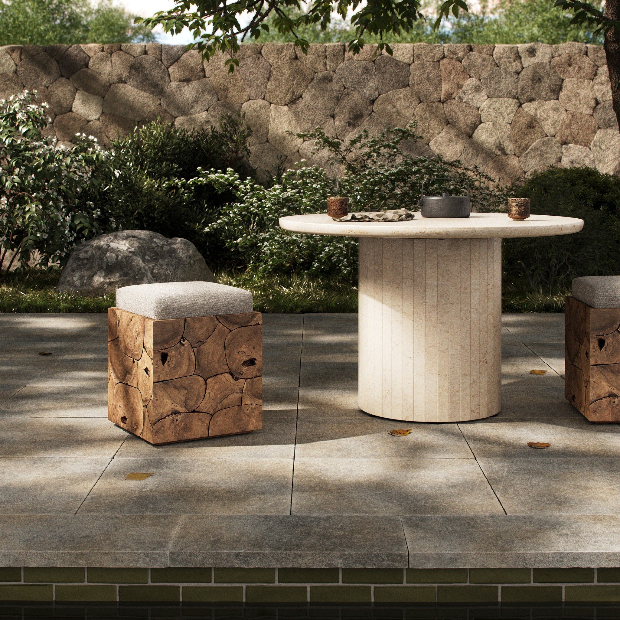Outdoor setting with a stone table and wooden stools against a stone wall.