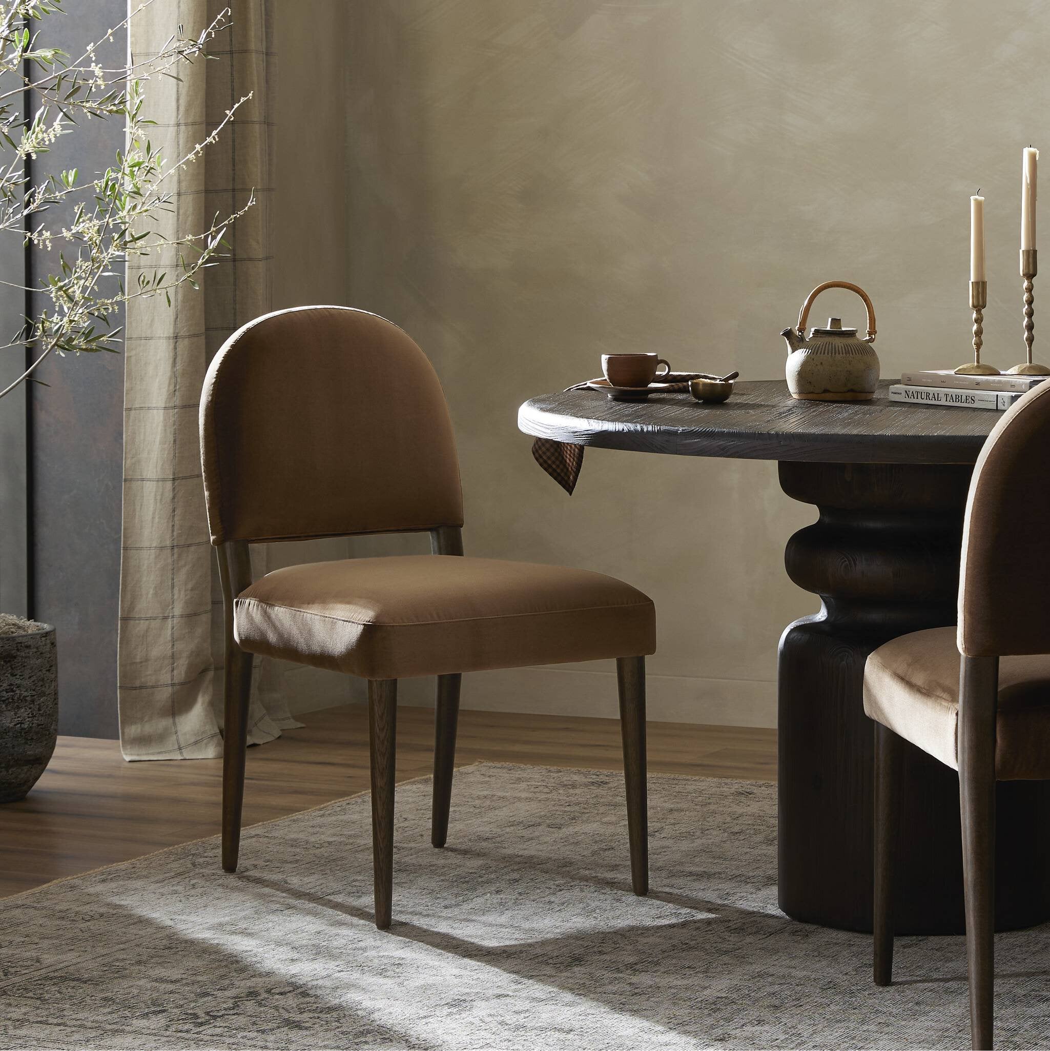 Brown chair in a dining room with a table and decor items.