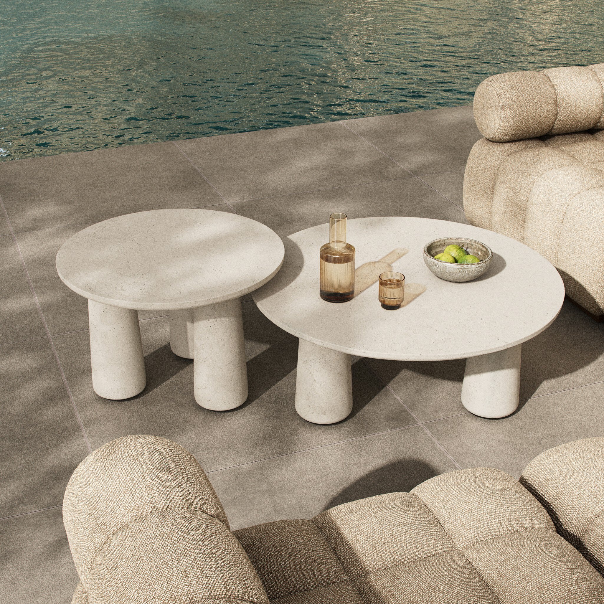 Outdoor setting with stone tables and chairs by a body of water