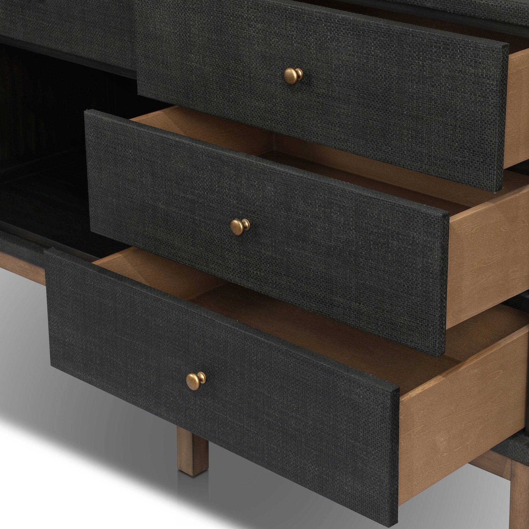 Wooden dresser with black drawers and gold knobs on a neutral background