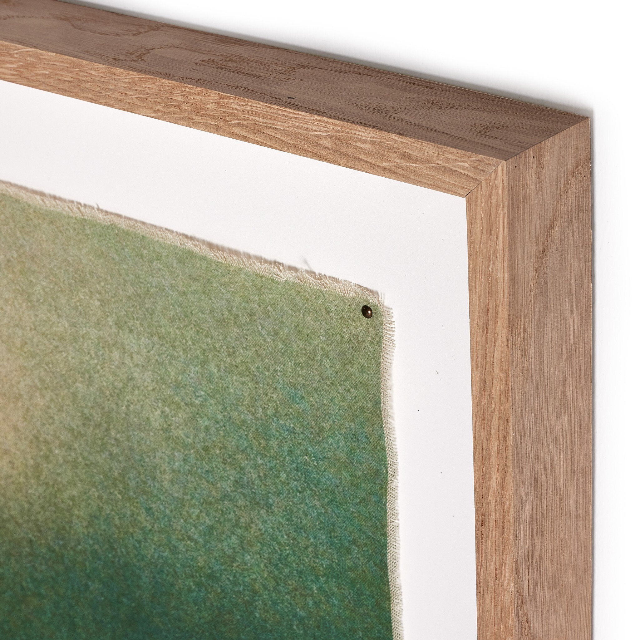 Close-up of a wooden frame with a green fabric corner on a white background