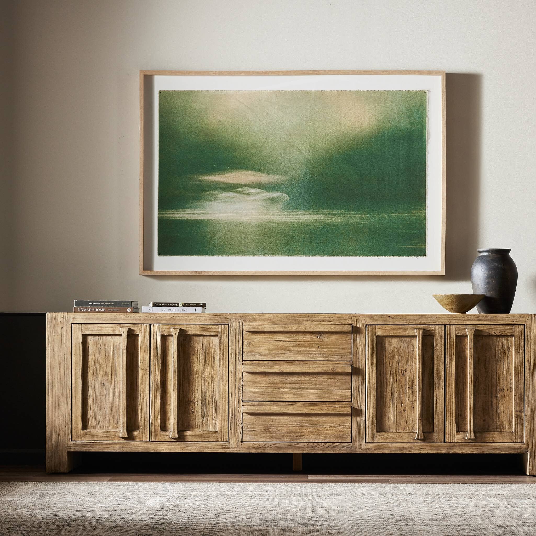Wooden sideboard with a large framed painting above it in a room.