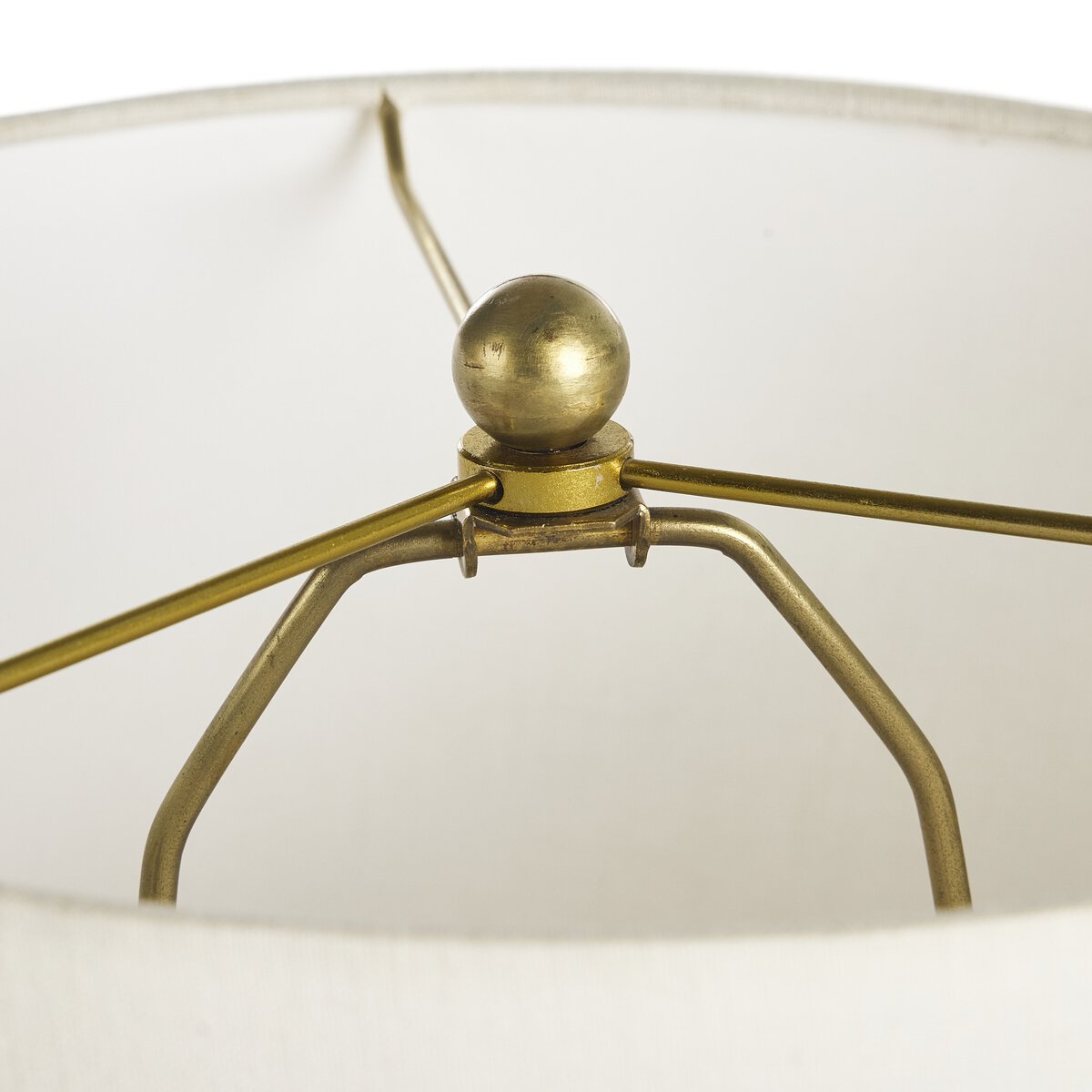 Close-up of a brass lamp with a white lampshade on a white background