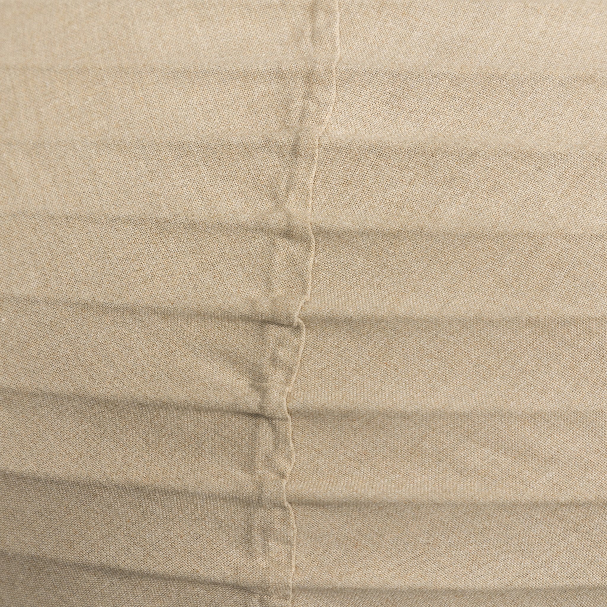Close-up of pleated beige fabric with a visible seam.