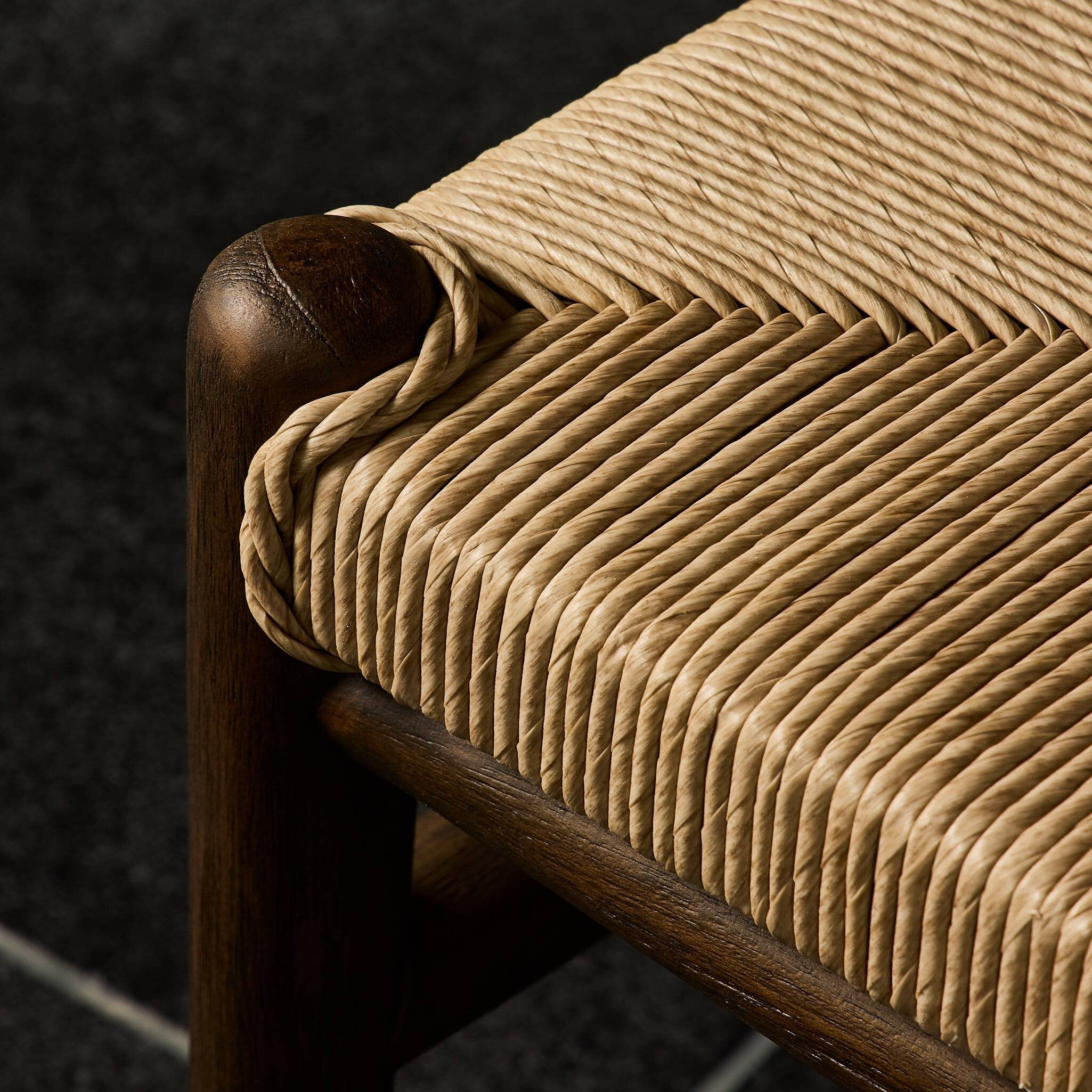Close-up of a chair with woven seat and wooden frame on a dark background