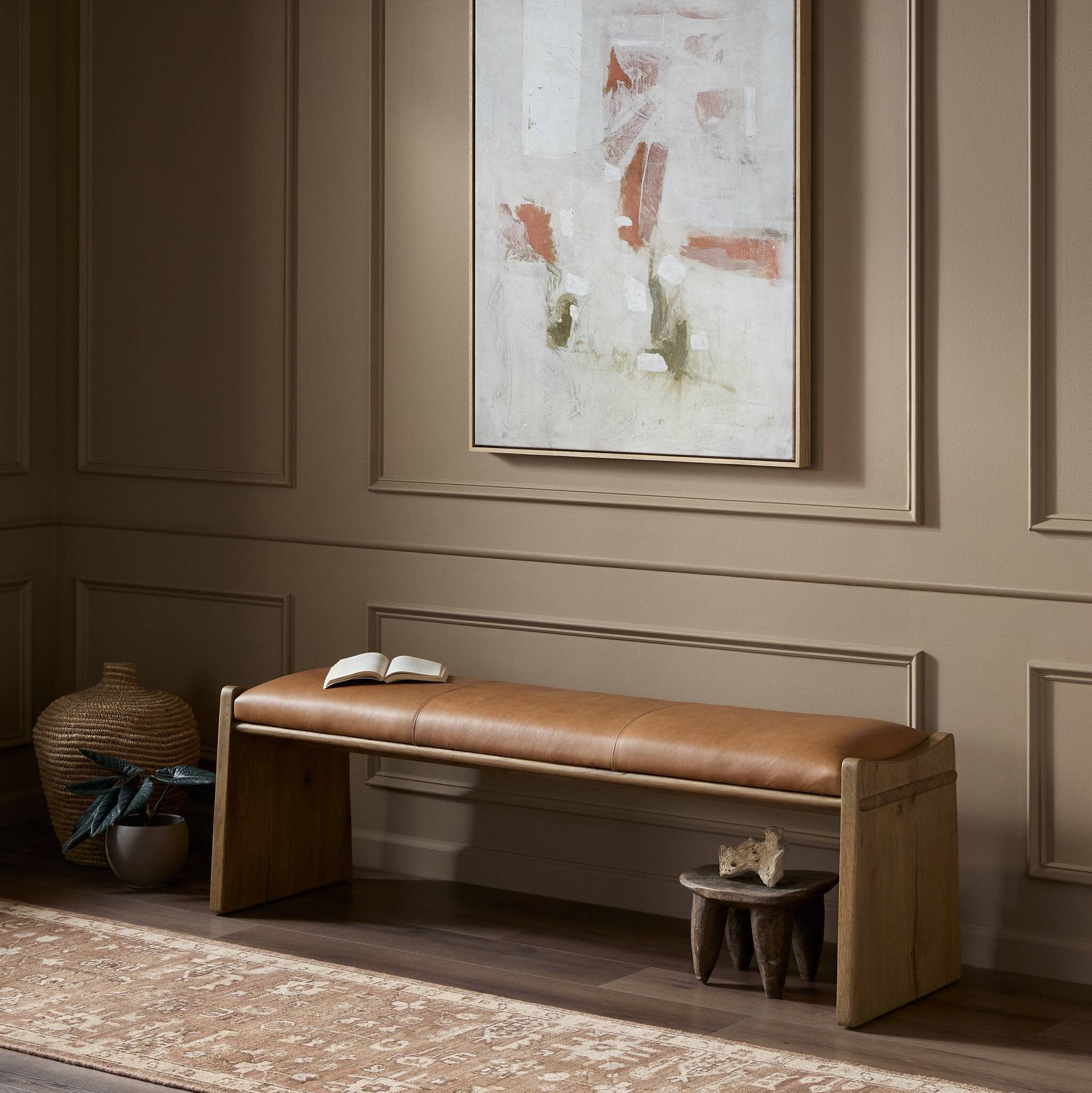 Brown leather bench in a room with abstract art on the wall