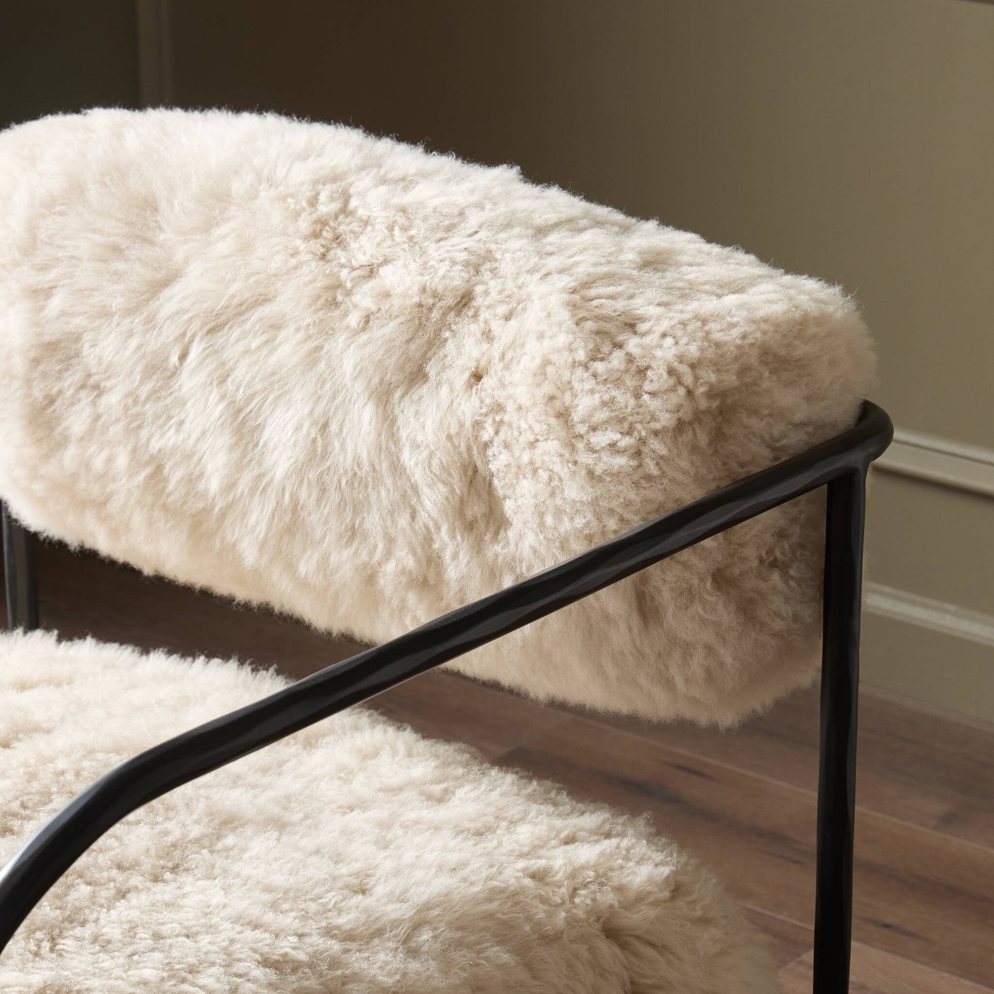 White fluffy bench with black metal frame on a wooden floor.