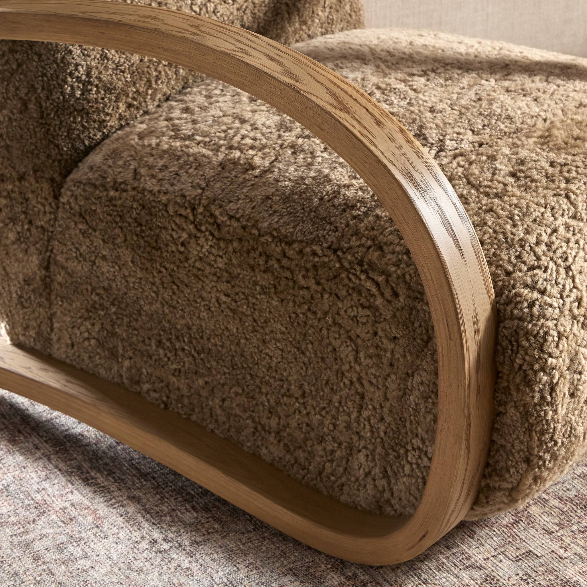 Close-up of a brown textured armchair with wooden armrests on a neutral background