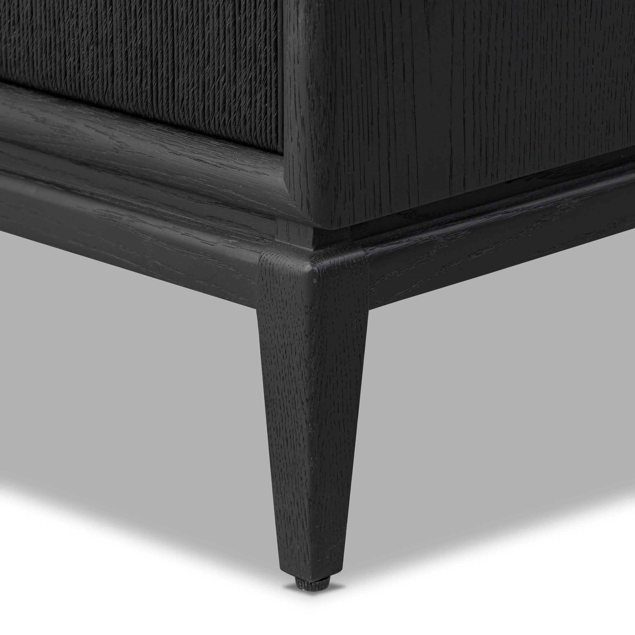 Close-up of a dark wooden nightstand leg on a light gray background