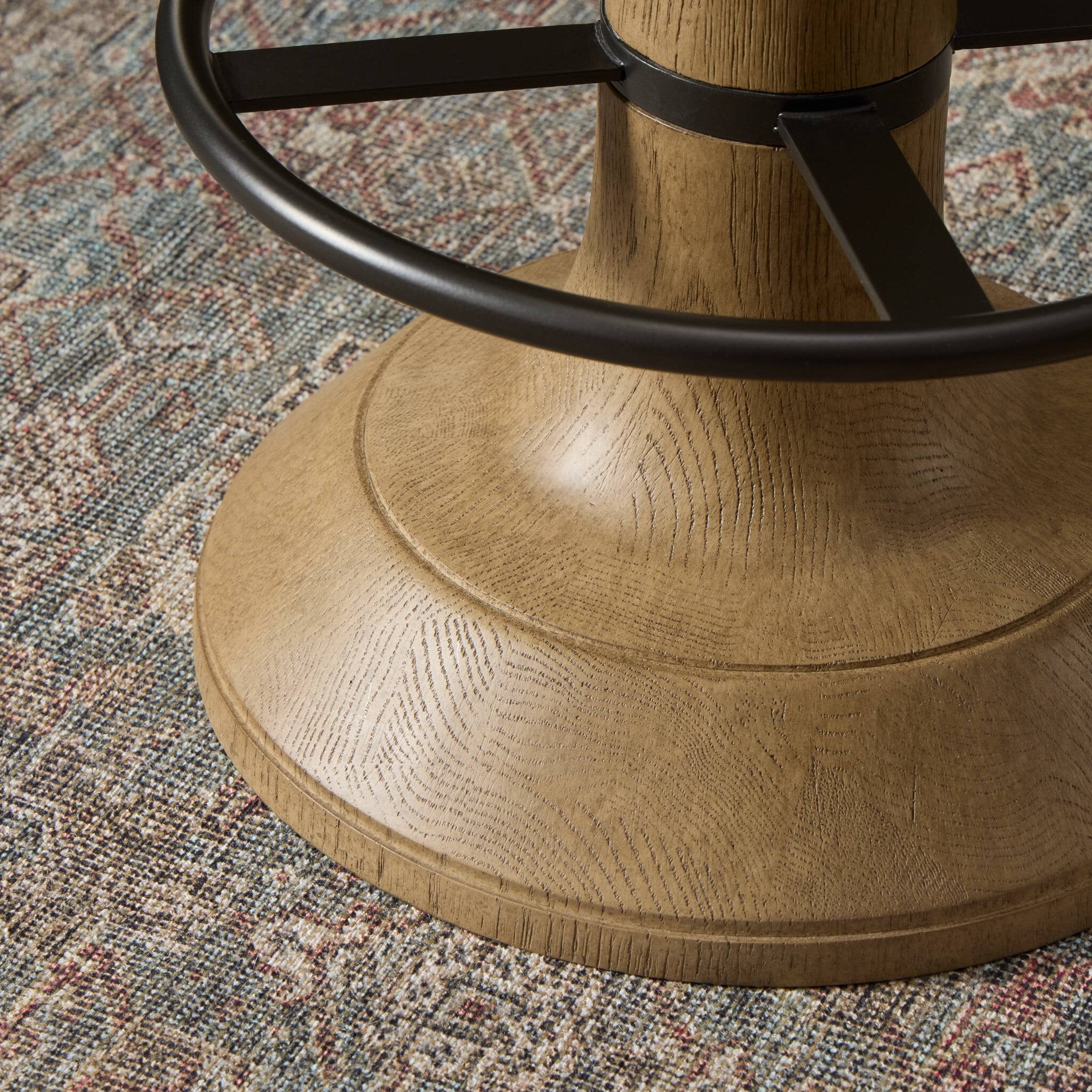 Wooden chair base with metal swivel mechanism on a patterned rug