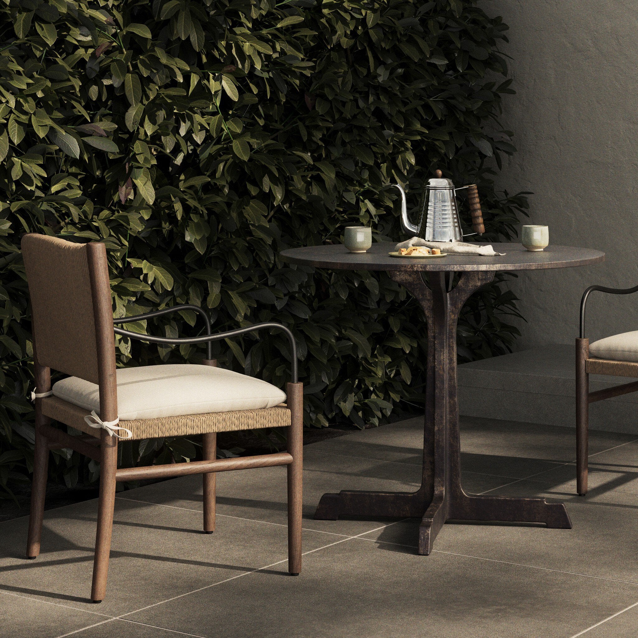 Outdoor setting with a table and chair against a green hedge.