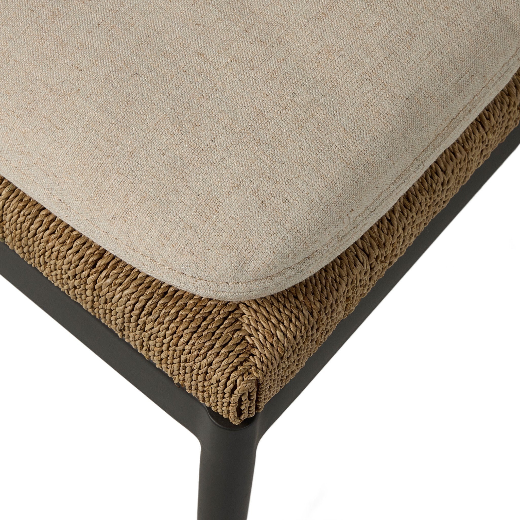 Close-up of a cushioned chair with beige fabric and woven brown trim on a white background