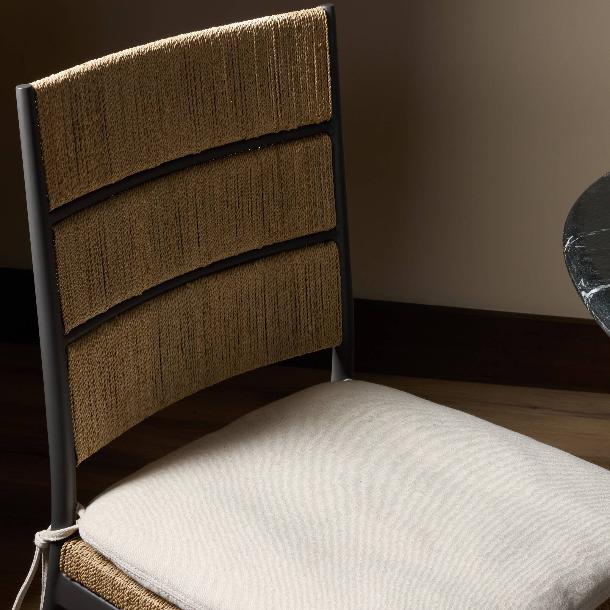 Chair with woven backrest and white cushion on a wooden floor.