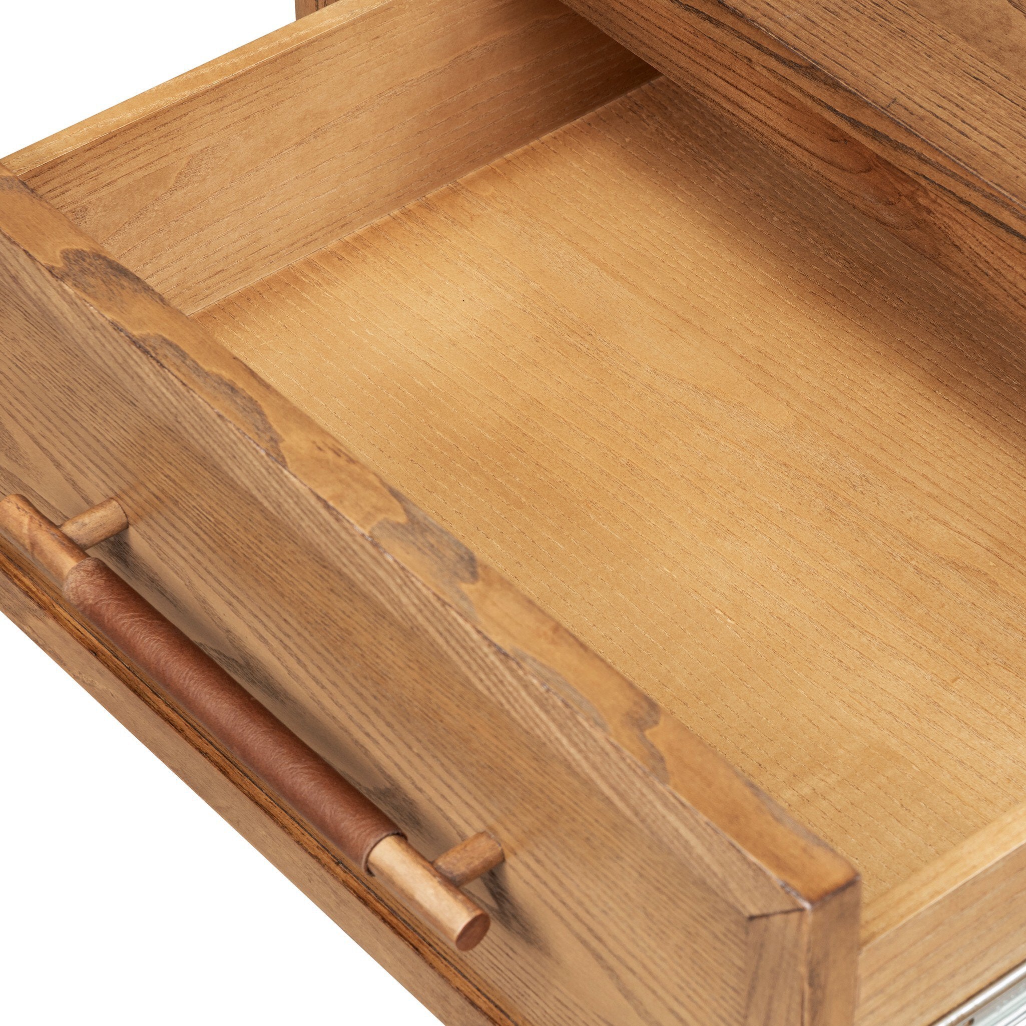 Close-up of a wooden drawer with a warm honey-toned wood finish and a cylindrical metal pull handle wrapped in brown material.