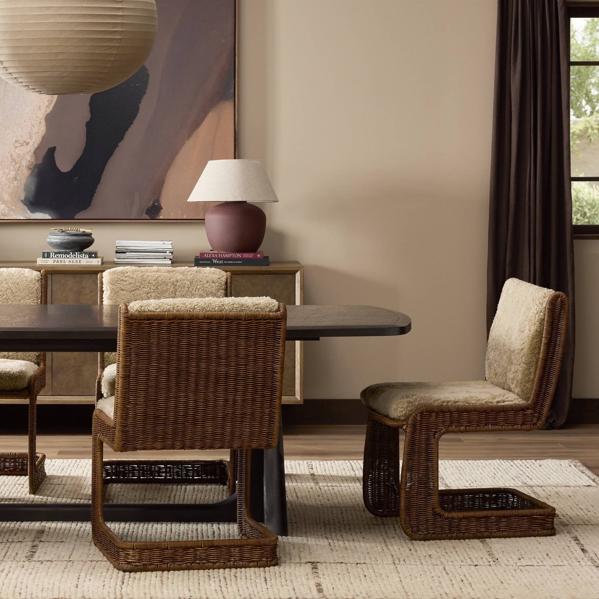 Dining room with wicker chairs and a lamp on a table.