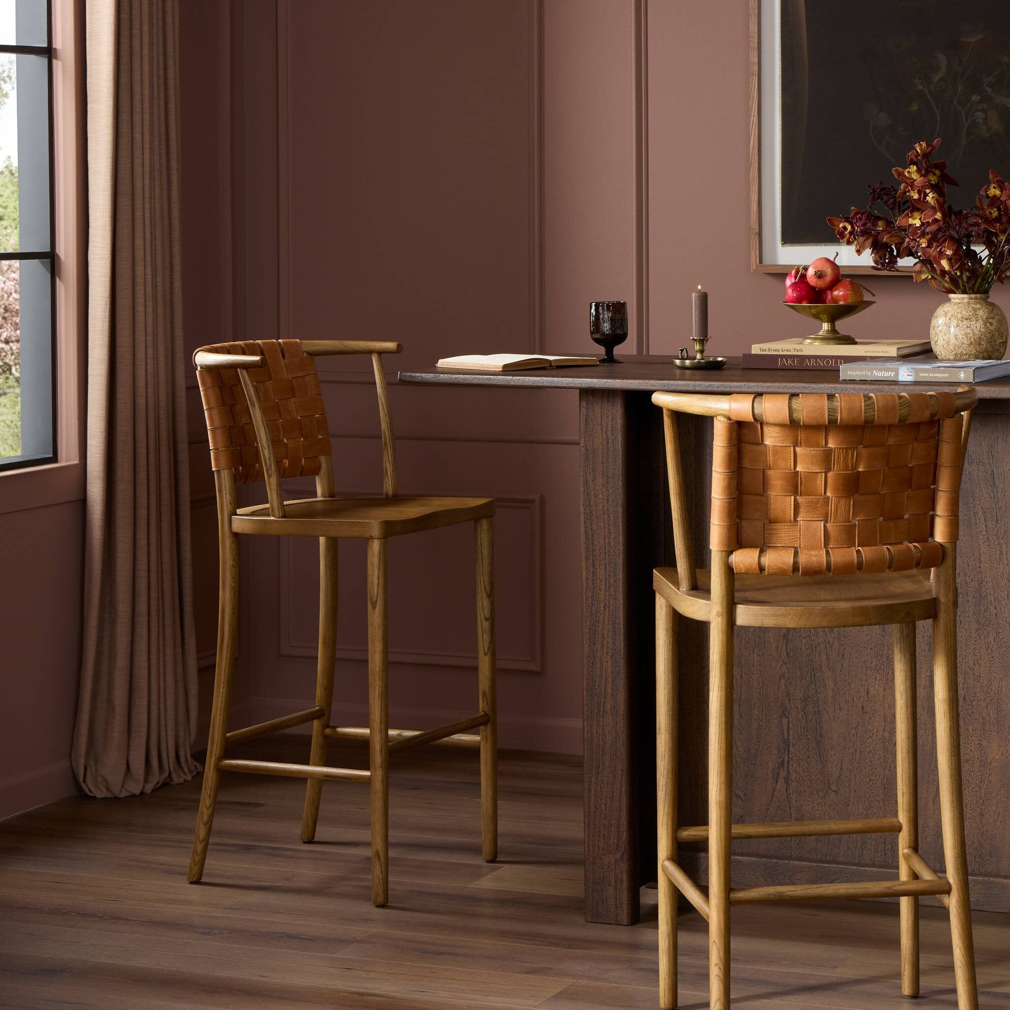 Dining area with wooden table and chairs against a pink wall.